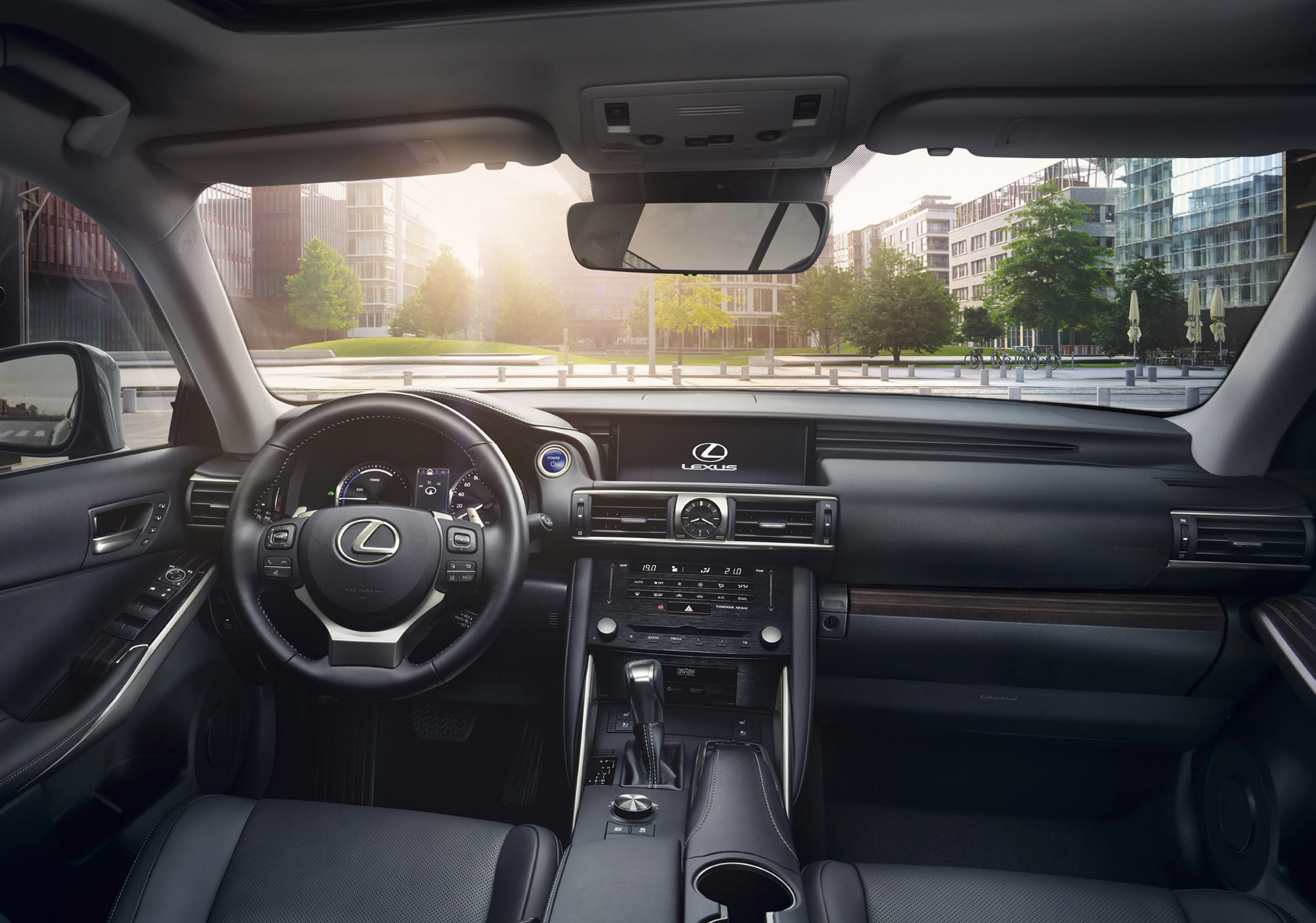 Innenansicht eines Lexus-Autos mit modernem Armaturenbrett und Steuer, im Hintergrund ein urbaner Ausblick durch die Windschutzscheibe.