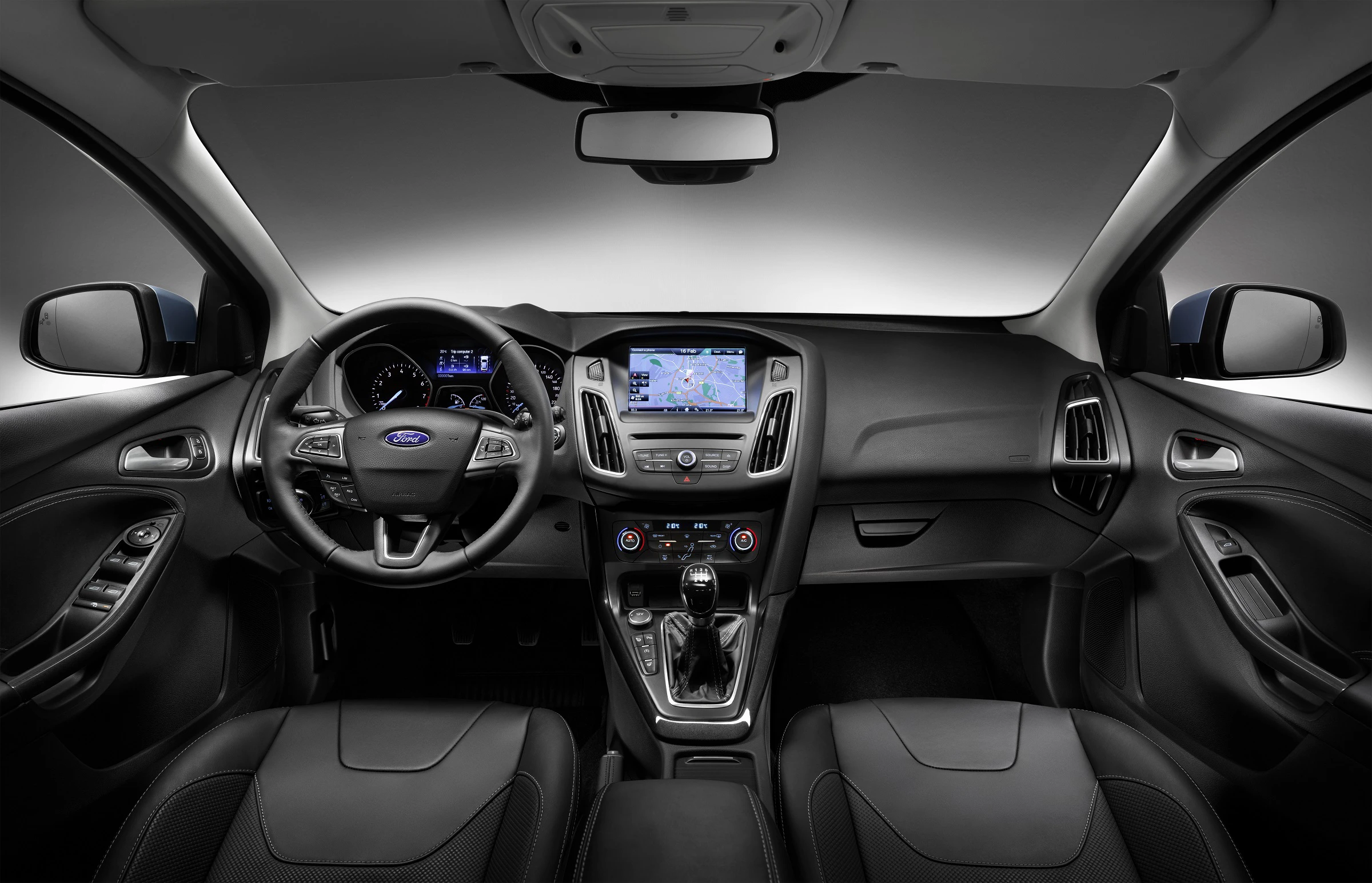 Innenraum eines modernen Autos mit Lenkrad, Mittelkonsole, Touchscreen-Navigationssystem und zwei Vordersitzen in dunkler Farbgebung.