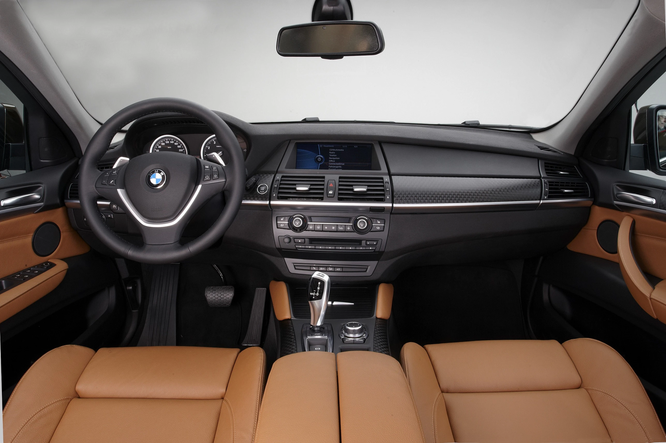 Innenraum eines BMW mit braunen Ledersitzen, modernem Armaturenbrett und Lenkrad, zentralem Display und elegantem Design.
