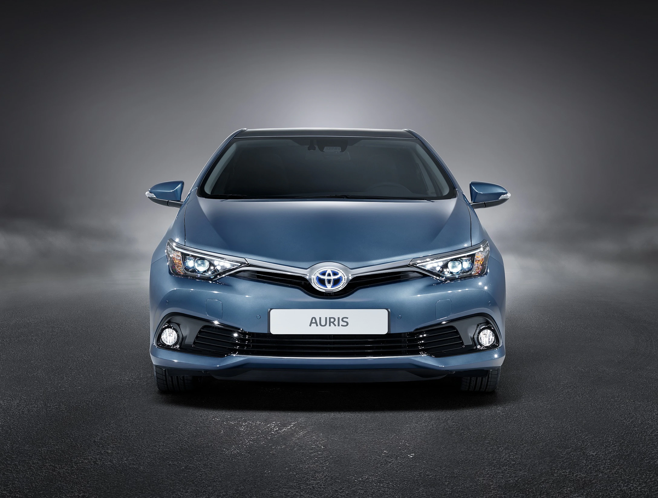 Blauer Toyota Auris von vorne, auf grauem Hintergrund mit dezentem Nebel, im Mittelpunkt der Aufnahme.