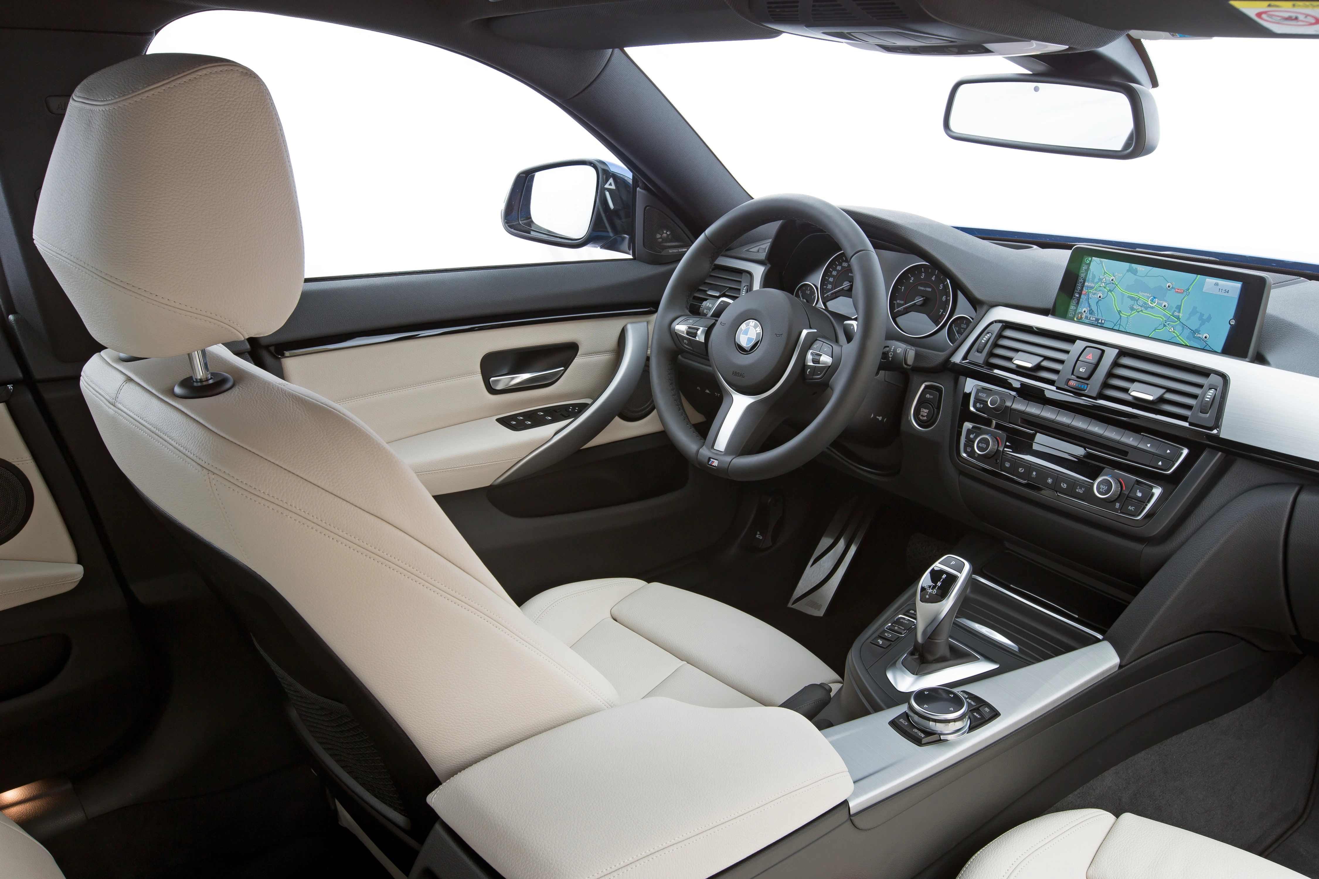 Innenraum eines Autos mit beigem Lederinterieur, modernem Lenkrad und Touchscreen-Navigationssystem auf dem Armaturenbrett.