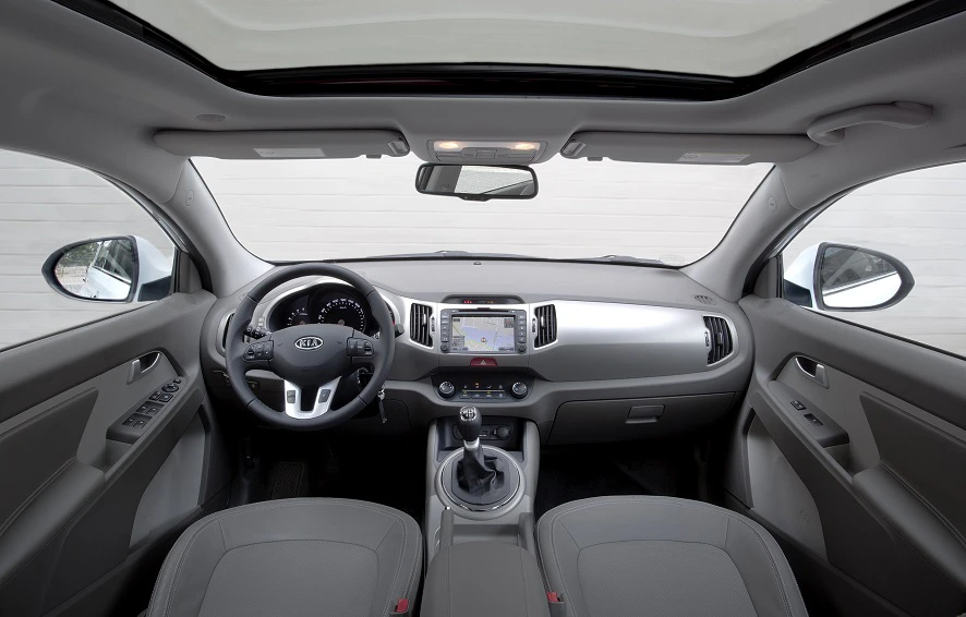 Innenraum eines Autos, abgebildet vom Rücksitz. Sicht auf Lenkrad, Schalthebel und ein Navigationssystem auf der Mittelkonsole.
