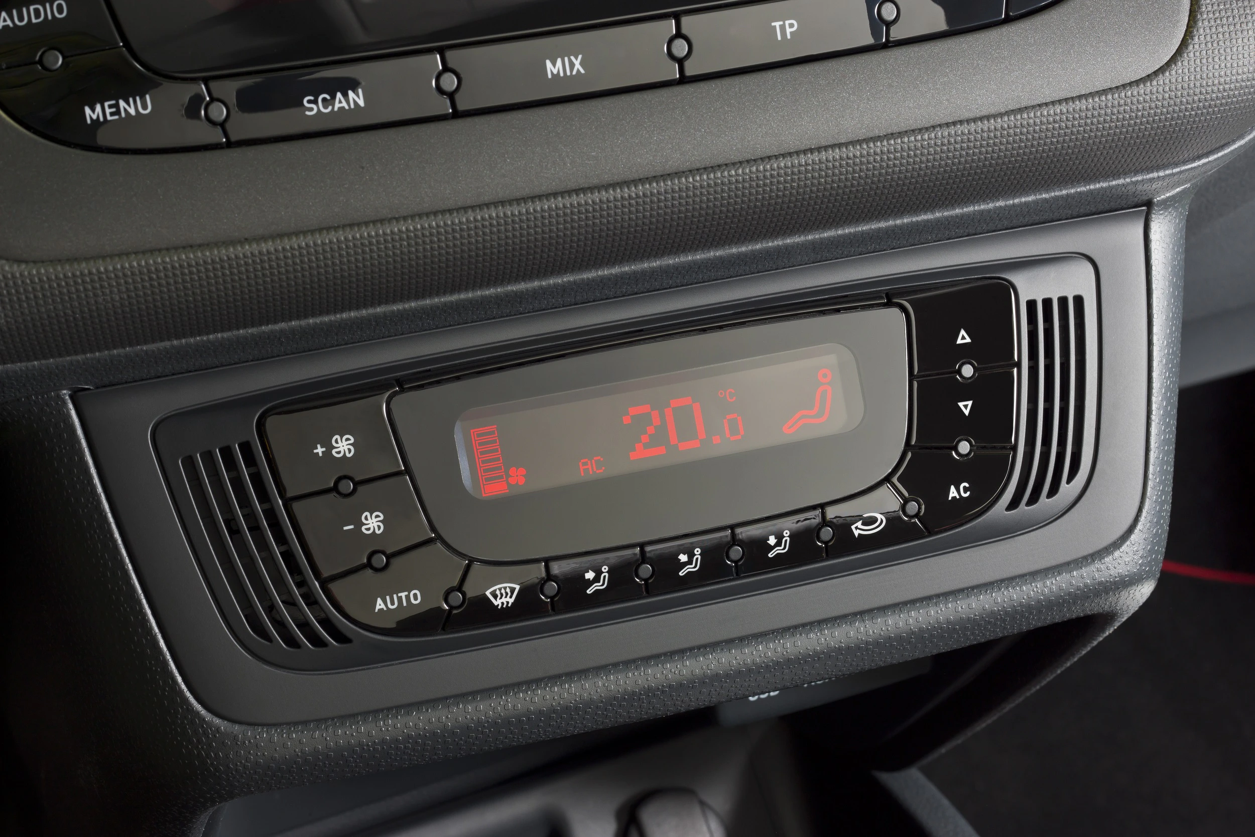 Nahaufnahme eines Auto-Klimaanlagen-Bedienfelds, zeigt eine Temperaturanzeige von 20 Grad Celsius und diverse Einstellknöpfe.
