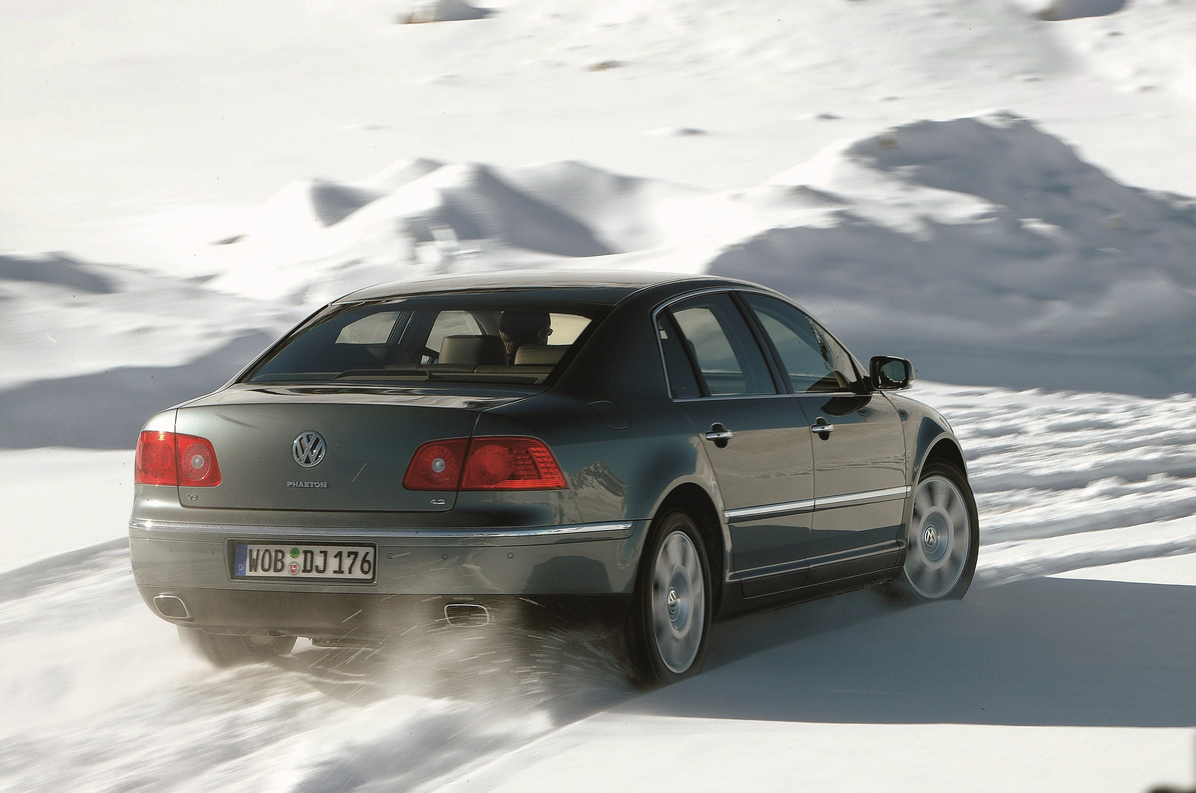 Ein Volkswagen Phaeton fährt durch schneebedecktes Gelände. Der Himmel ist klar, und das Auto hinterlässt Spuren im Schnee.