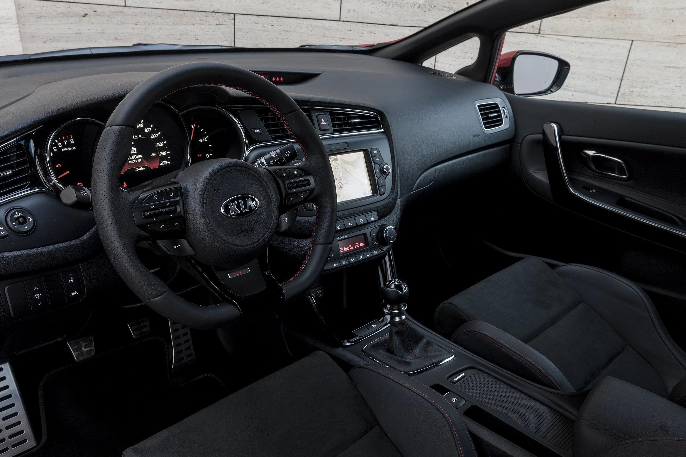 Schwarzer Autoinnenraum mit Lederlenkrad, Armaturenbrett, manuellem Schaltknüppel und Touchscreen. Modern und elegant gestaltet.