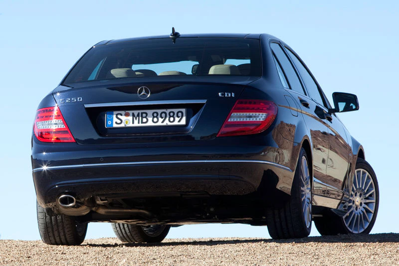 Rückansicht eines schwarzen Mercedes-Benz C250 CDI auf einer sandigen Fläche unter klarem Himmel. Nummernschild S•MB 8989.