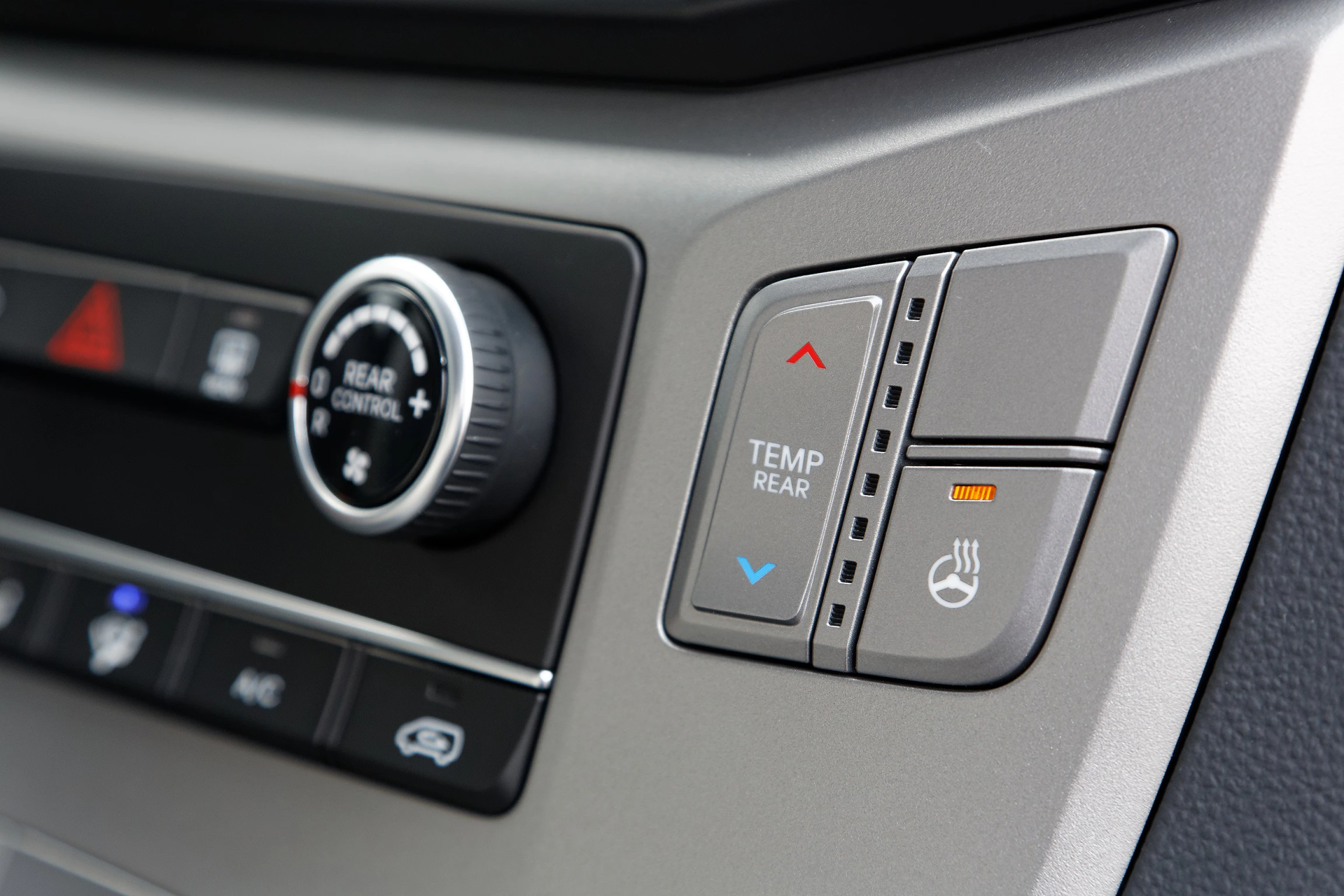 Bedienelemente im Auto für Temperatur und Sitzheizung: Temperaturregler mit blauer und roter Markierung, Symbol für beheizten Sitz.