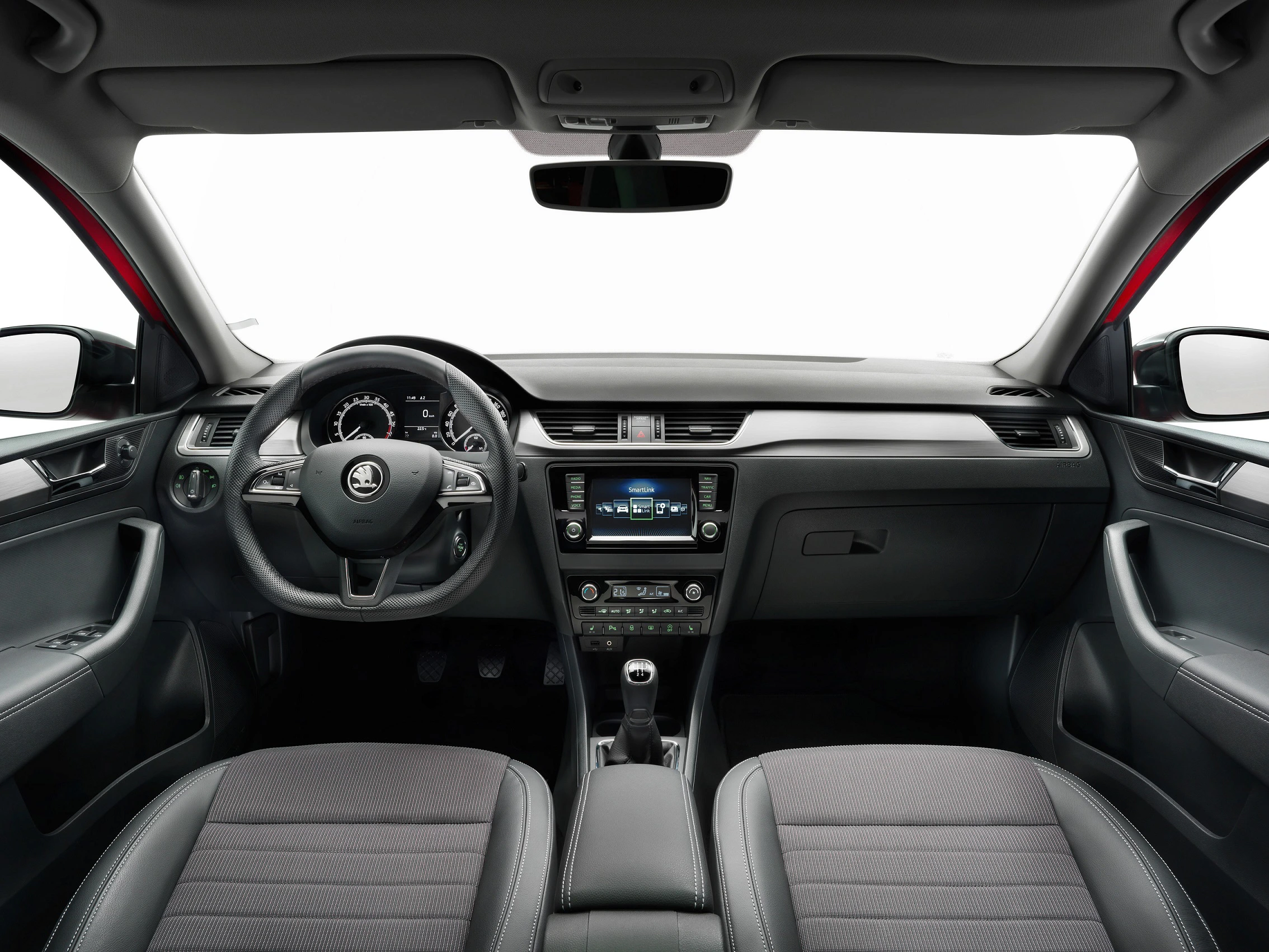 Innenraum eines Autos mit modernem Armaturenbrett, Lenkrad und Mittelkonsolen-Display, graue Polstersitze und schwarze Akzente.
