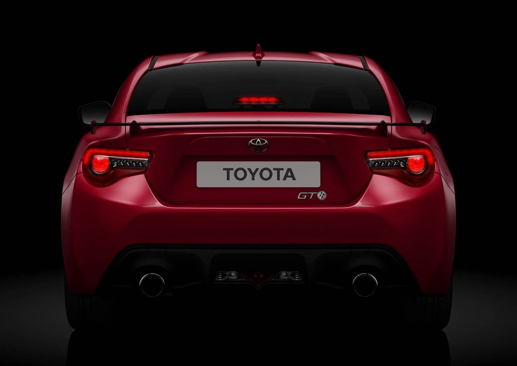 Rückansicht eines roten Toyota GT86, beleuchtet auf dunklem Hintergrund, zeigt Rückscheinwerfer und Embleme.