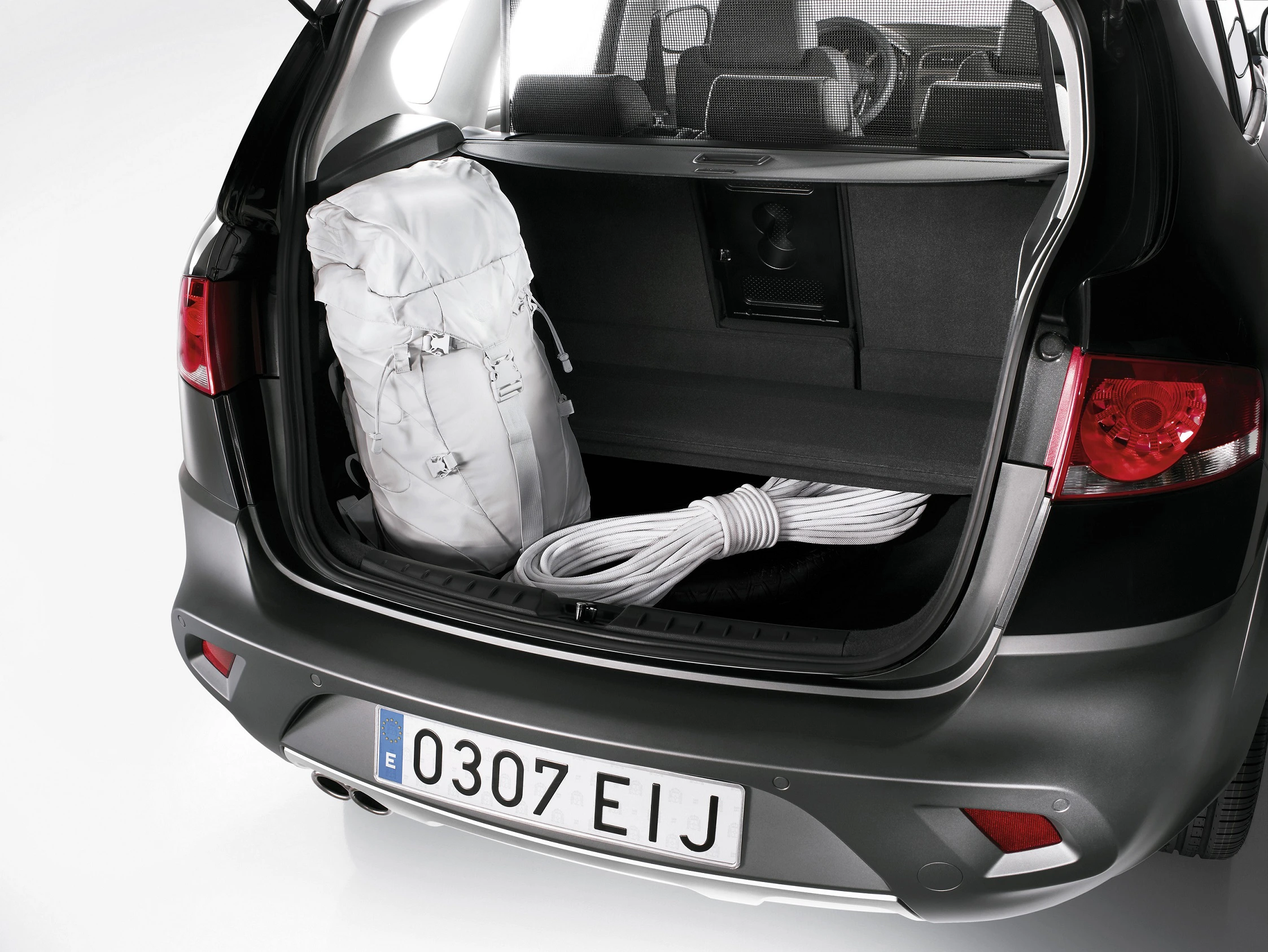 Ein geöffneter Kofferraum eines Autos mit einem weißen Rucksack und einem aufgerollten Seil im Laderaum.