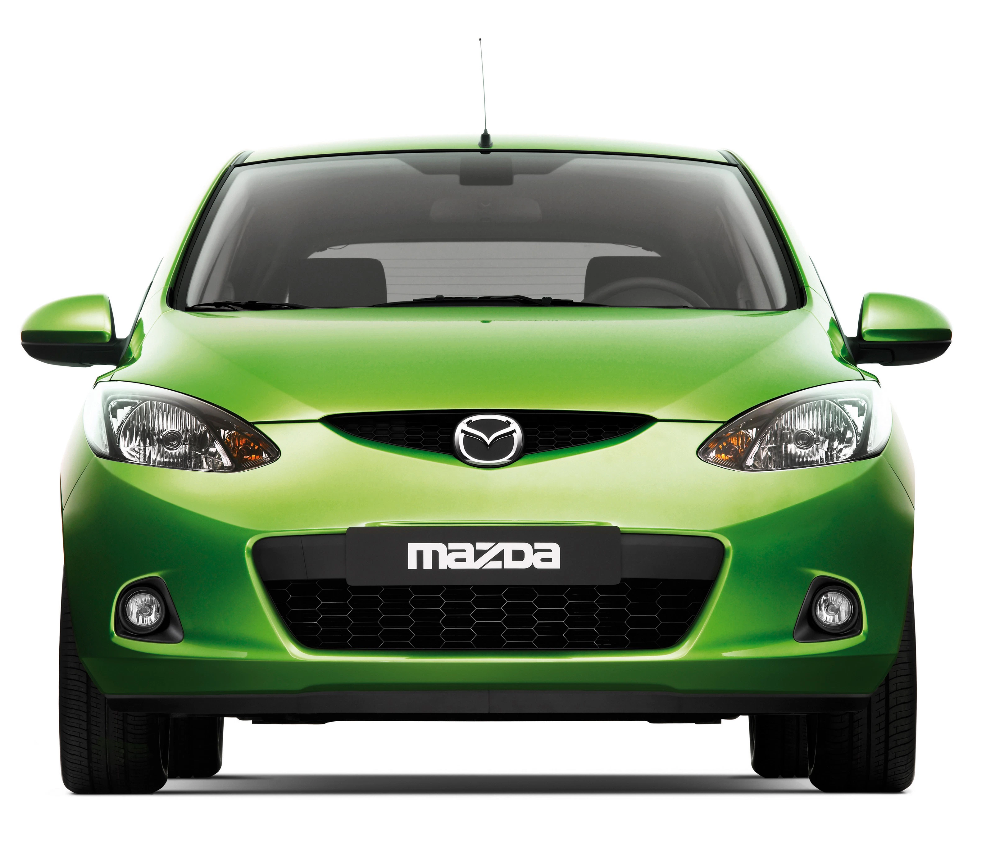 Grünes Auto von vorne mit Mazda-Logo auf dem Kühlergrill, helle Scheinwerfer und glänzende Lackierung.