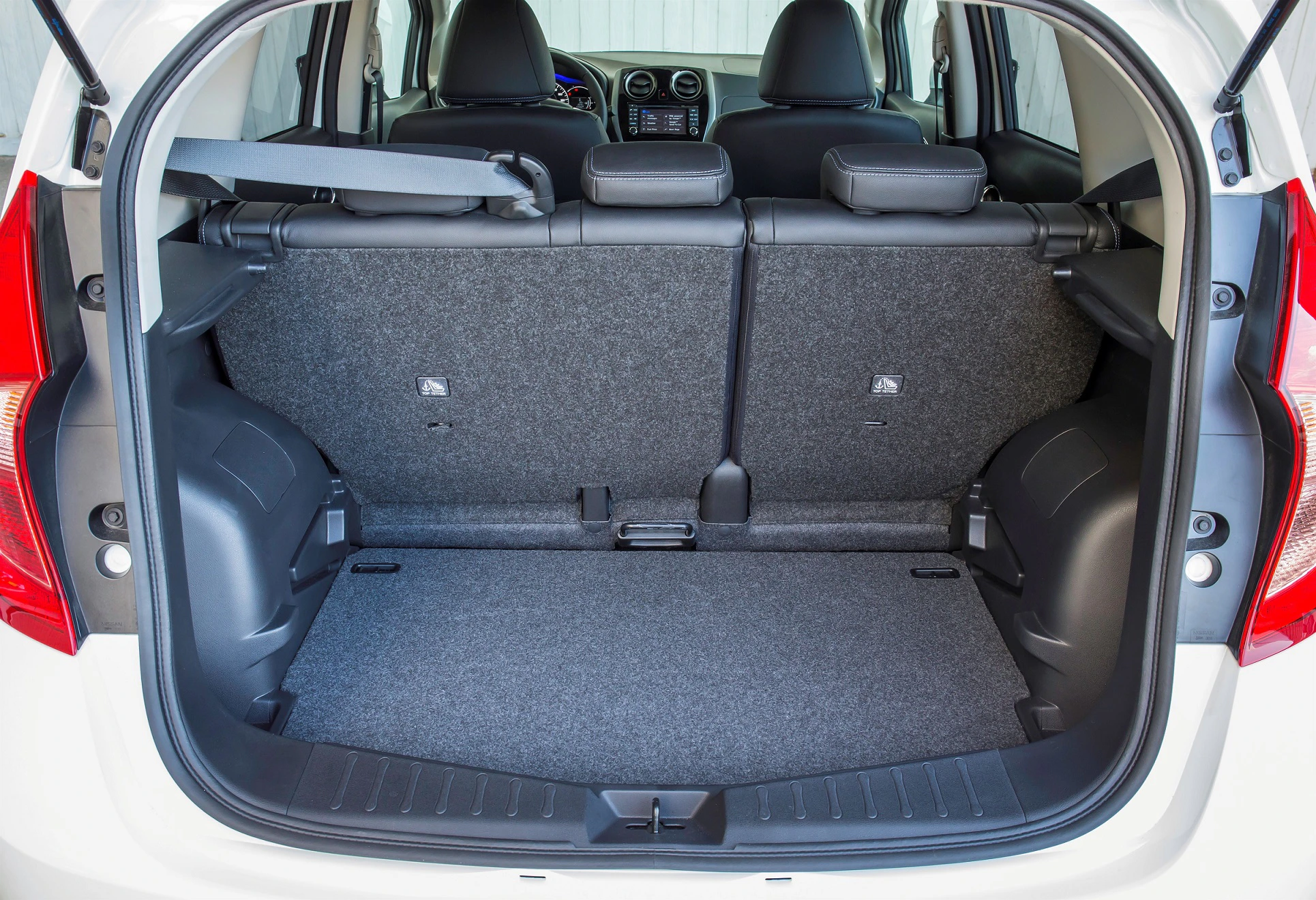 Kofferraum eines Autos mit umgeklappten Rücksitzen, grauer Teppichboden und Sicht auf das Armaturenbrett.