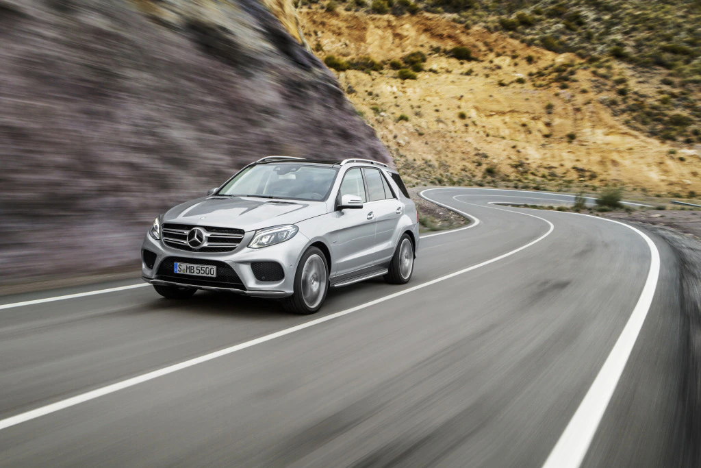 Silberner SUV von Mercedes-Benz fährt auf einer kurvigen Bergstraße bei Tageslicht, umgeben von felsiger Landschaft.