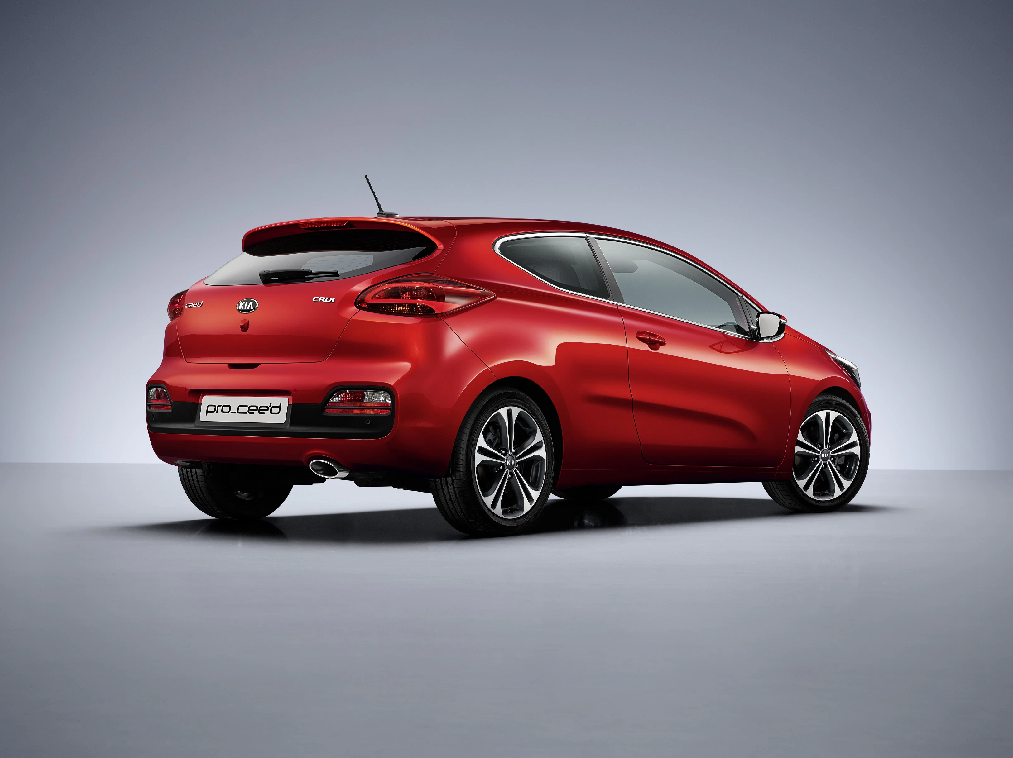 Roter Sportwagen mit elegantem Design, von hinten links betrachtet, auf grauem Studioboden stehend.