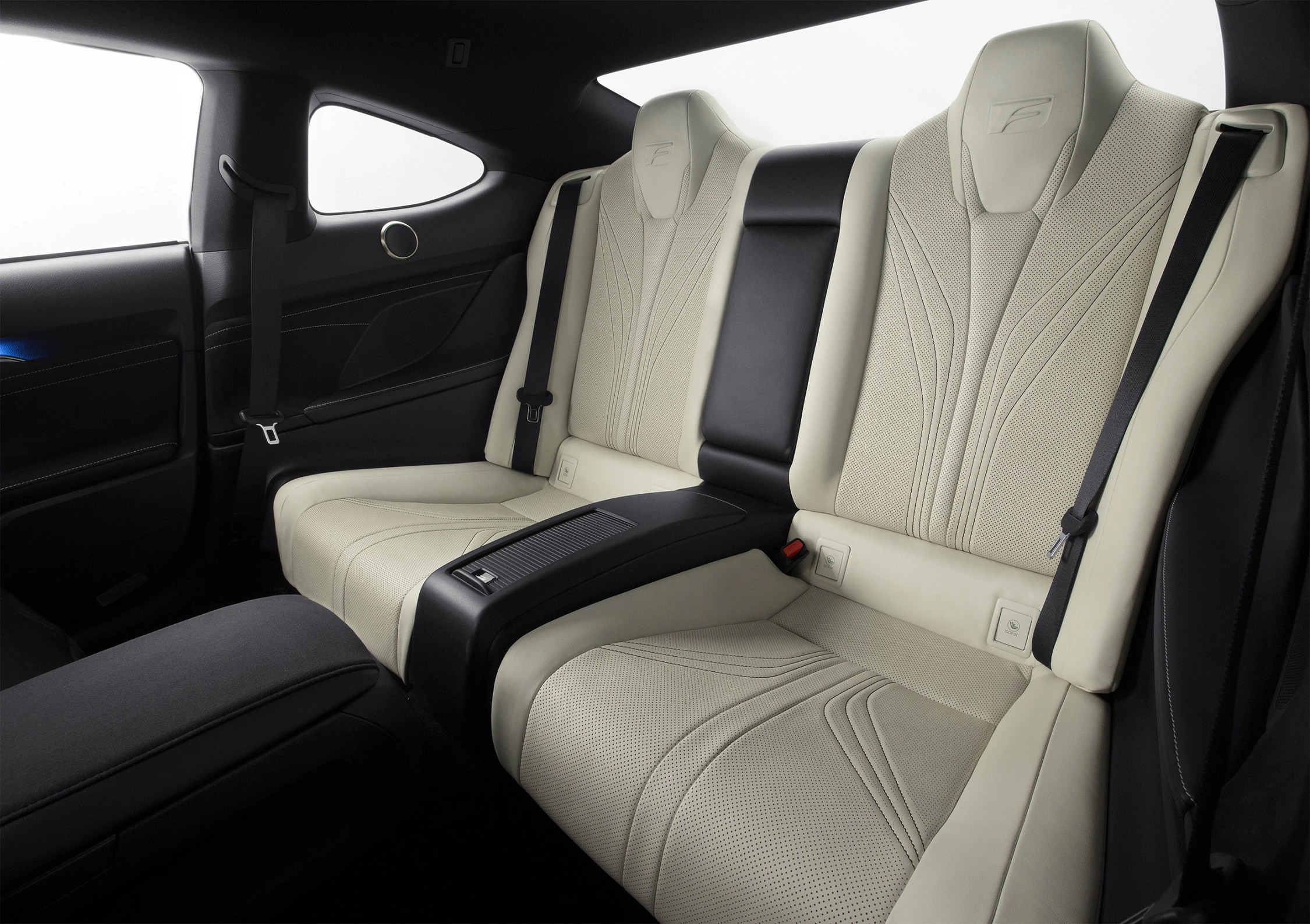 Rücksitze eines Autos mit beigefarbenem Lederbezug und modernem Design, schwarze Armlehnen, helle Innenausstattung.