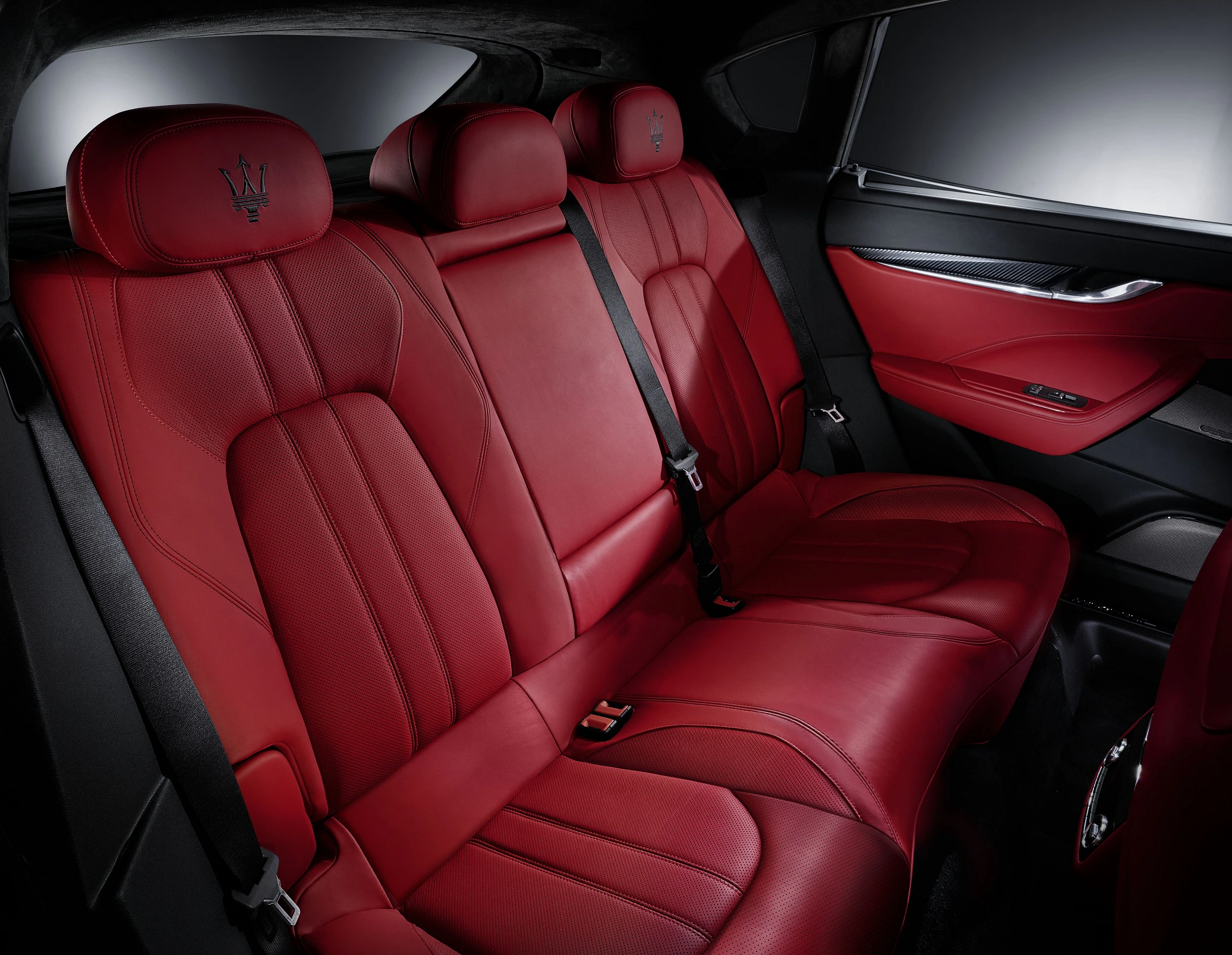 Roter Ledersitz eines Luxusautos mit stilvollen Details und hohem Komfort, umgeben von einem dunklen Innenraum.