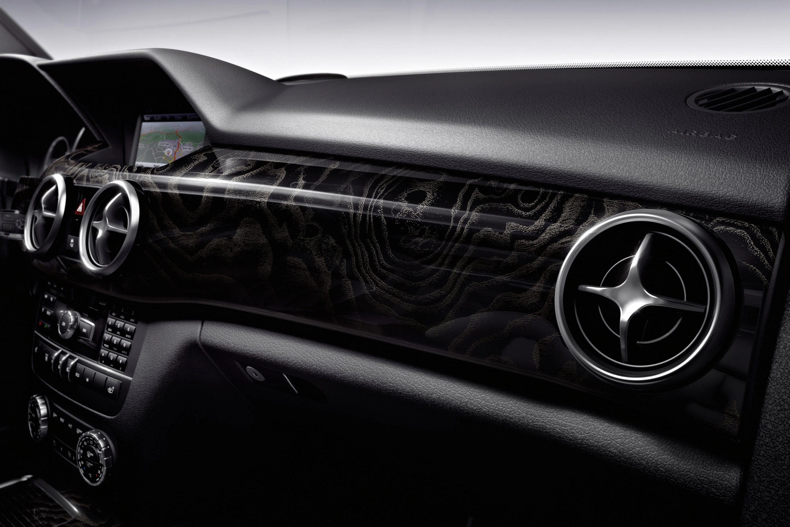 Armaturenbrett eines Autos mit stilvollem, schwarzem Design, Lüftungsdüsen in Sternform und einem eingebauten Bildschirm im Hintergrund.