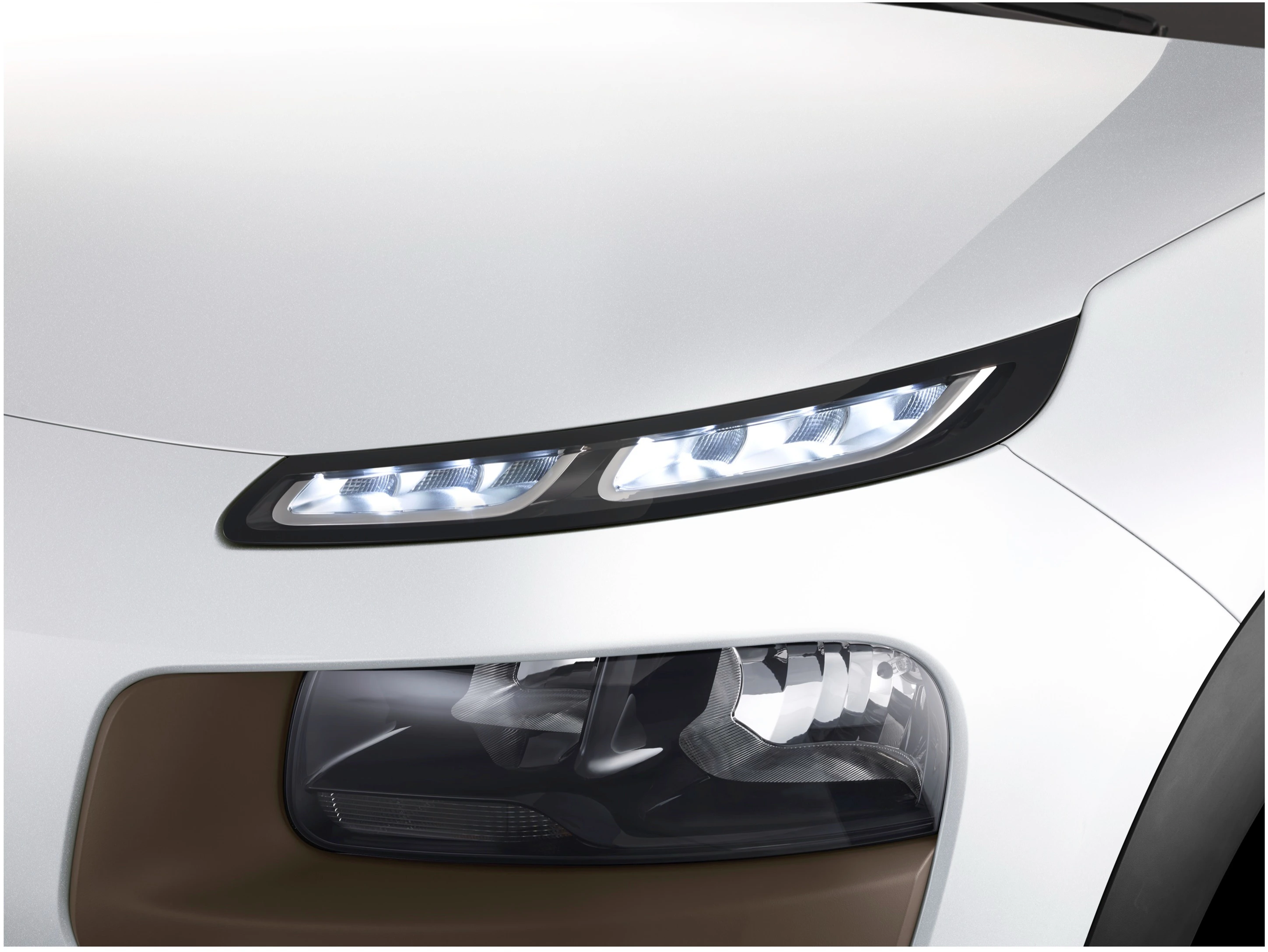 Nahaufnahme eines weißen Autos mit schlanken LED-Tagfahrlichtern und einem markanten Scheinwerferdesign.