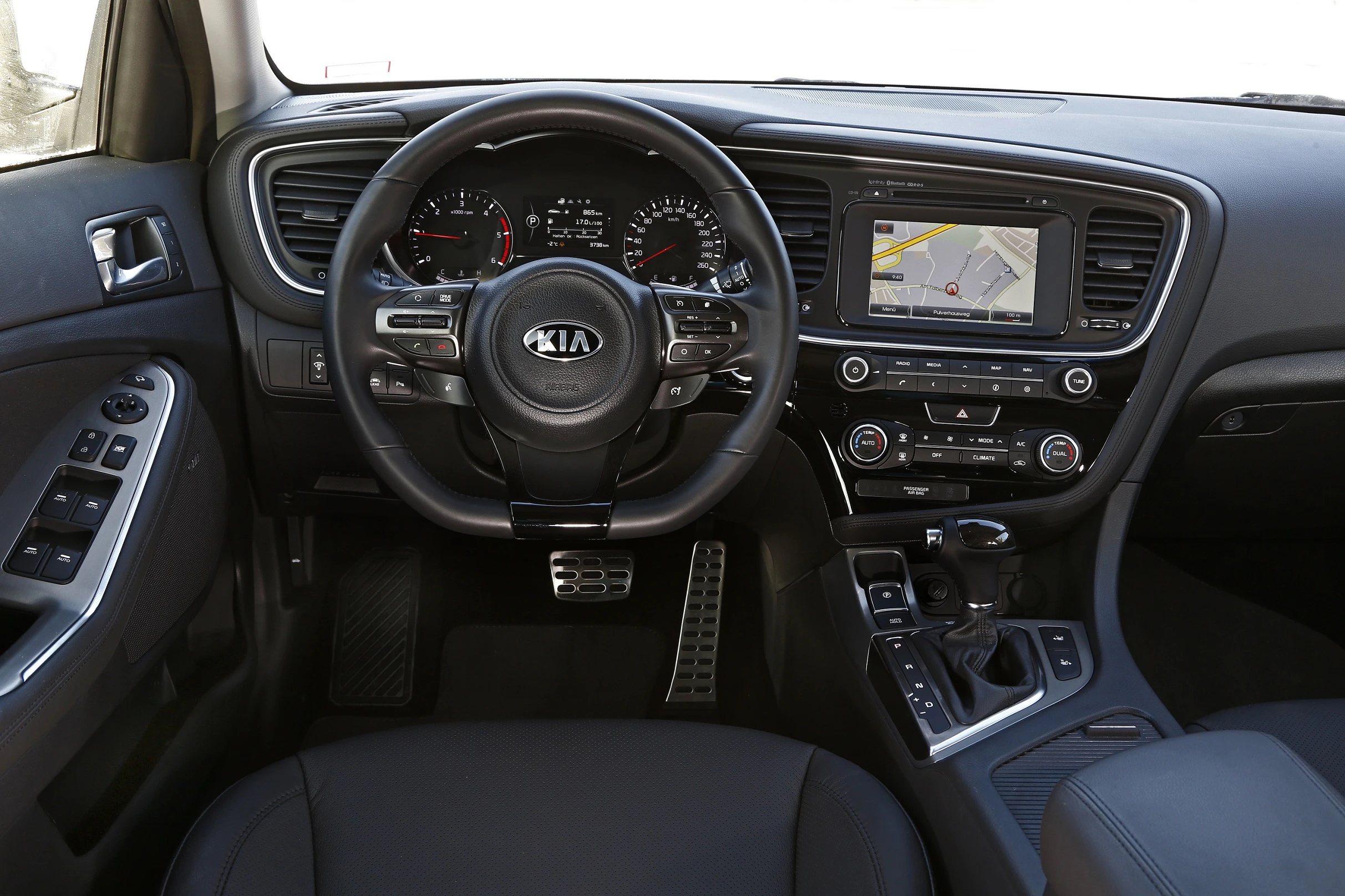 Innenraum eines KIA-Fahrzeugs mit Lenkrad, Armaturenbrett, Touchscreen-Navigation und Bedienelementen.