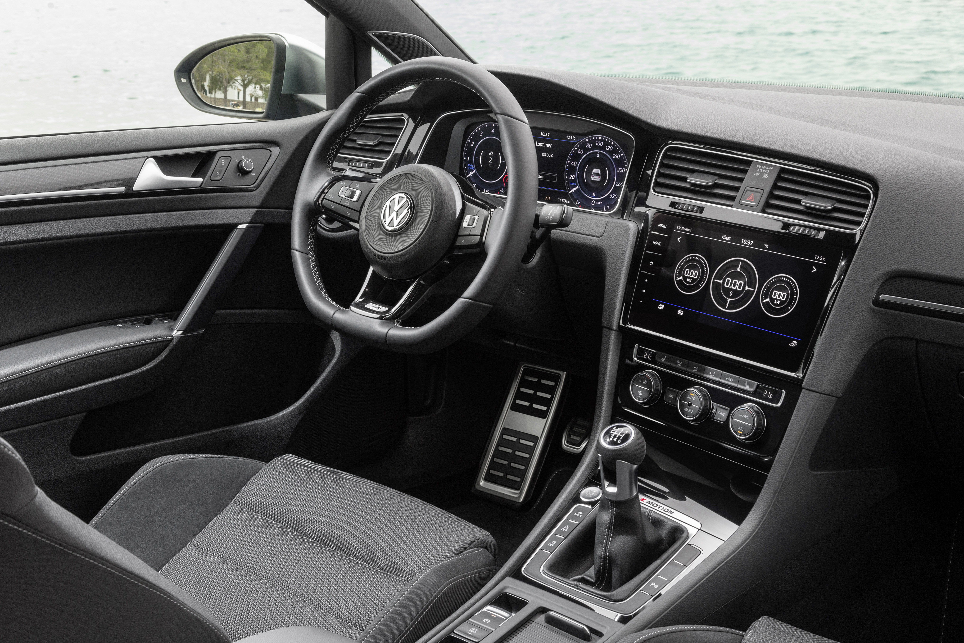Innenraum eines Volkswagen-Autos mit modernem Armaturenbrett, Lederlenkrad, Touchscreen-Display und Schaltgetriebe.