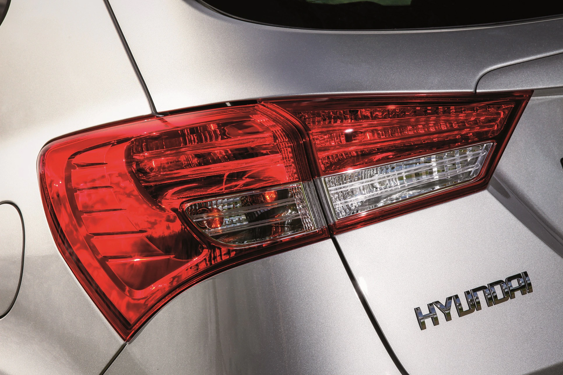 Detailaufnahme eines silbernen Hyundai mit prominentem, leuchtend roten Rücklicht und Logo auf der Heckklappe.