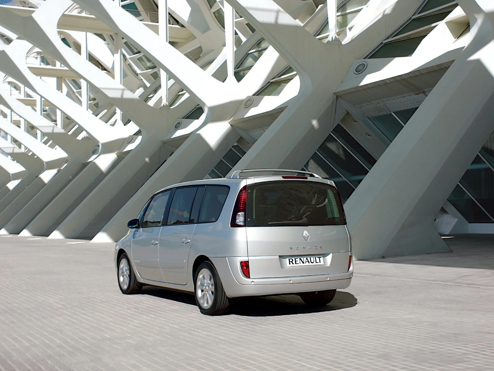 Silberner Renault Espace vor moderner Architektur mit geometrischem Design und vielen diagonalen Linien.