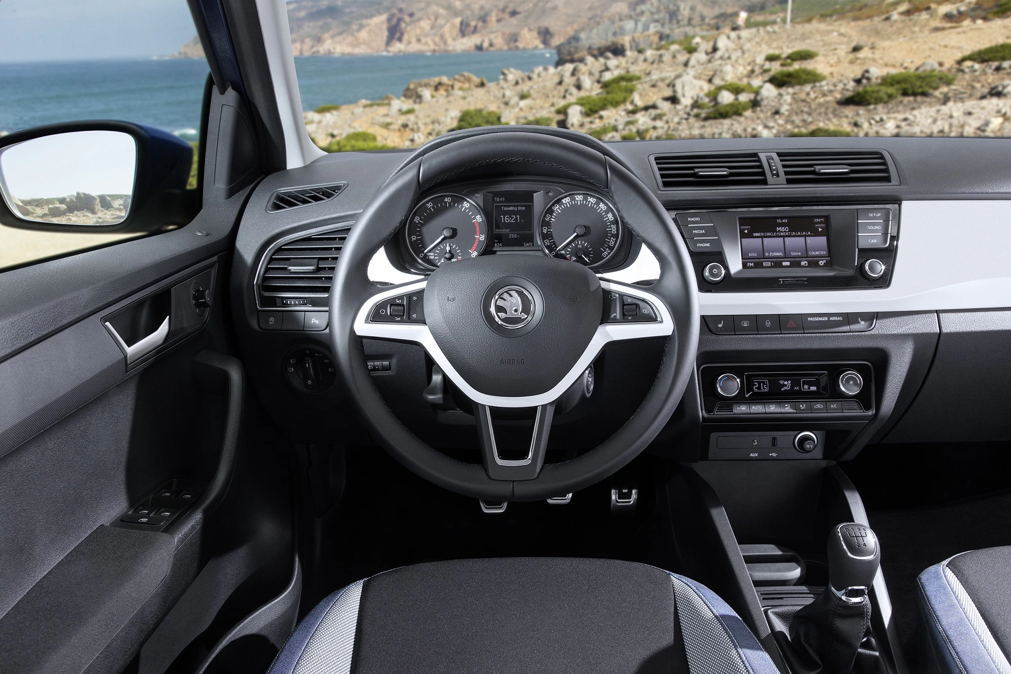 Innenraum eines Autos mit Lenkrad, Armaturenbrett und Meeresblick durch die Windschutzscheibe. Modernes Design mit klarer Anzeige.