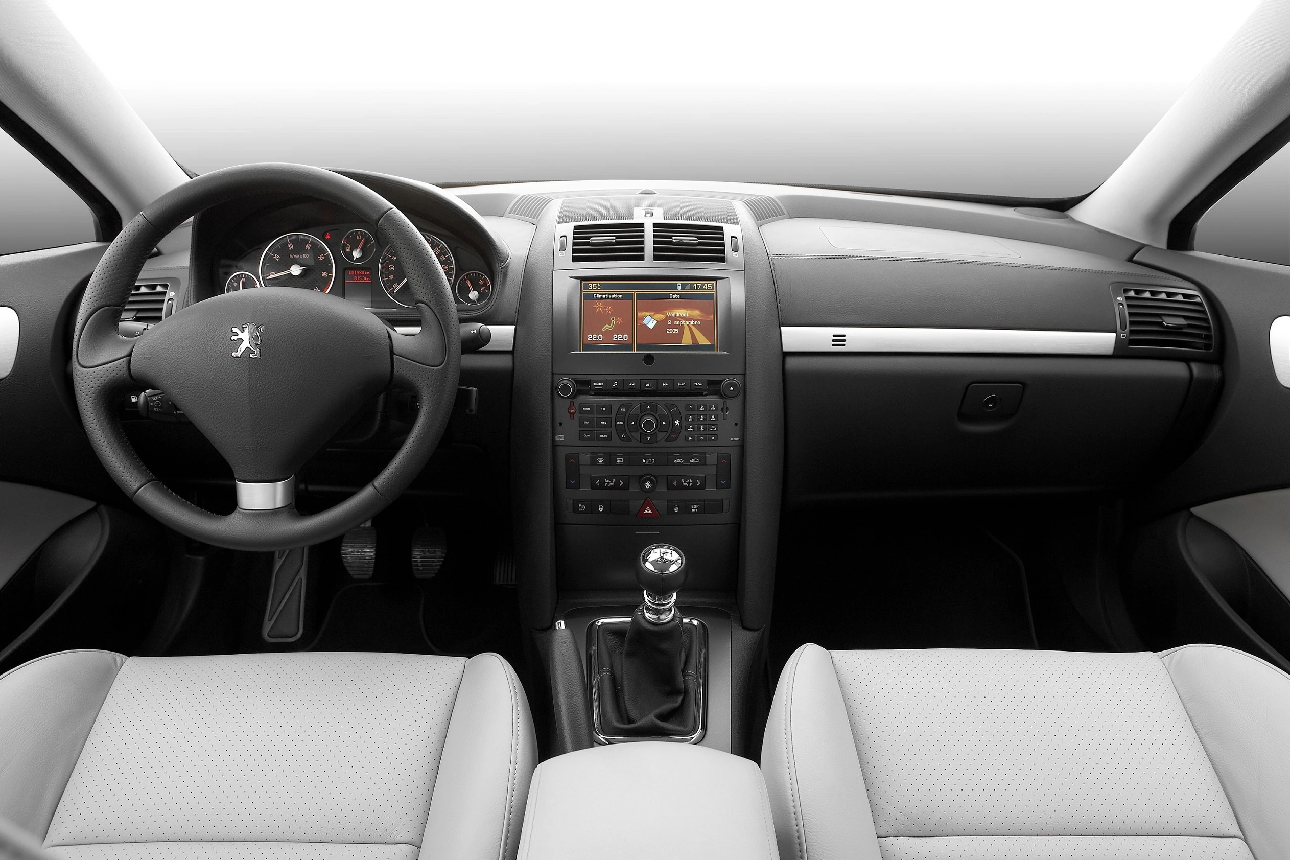 Innenraum eines Autos mit grauen Sitzen, Lenkrad mit Peugeot-Logo, Schalthebel, Infotainment-Bildschirm und Armaturenbrett-Anzeigen.