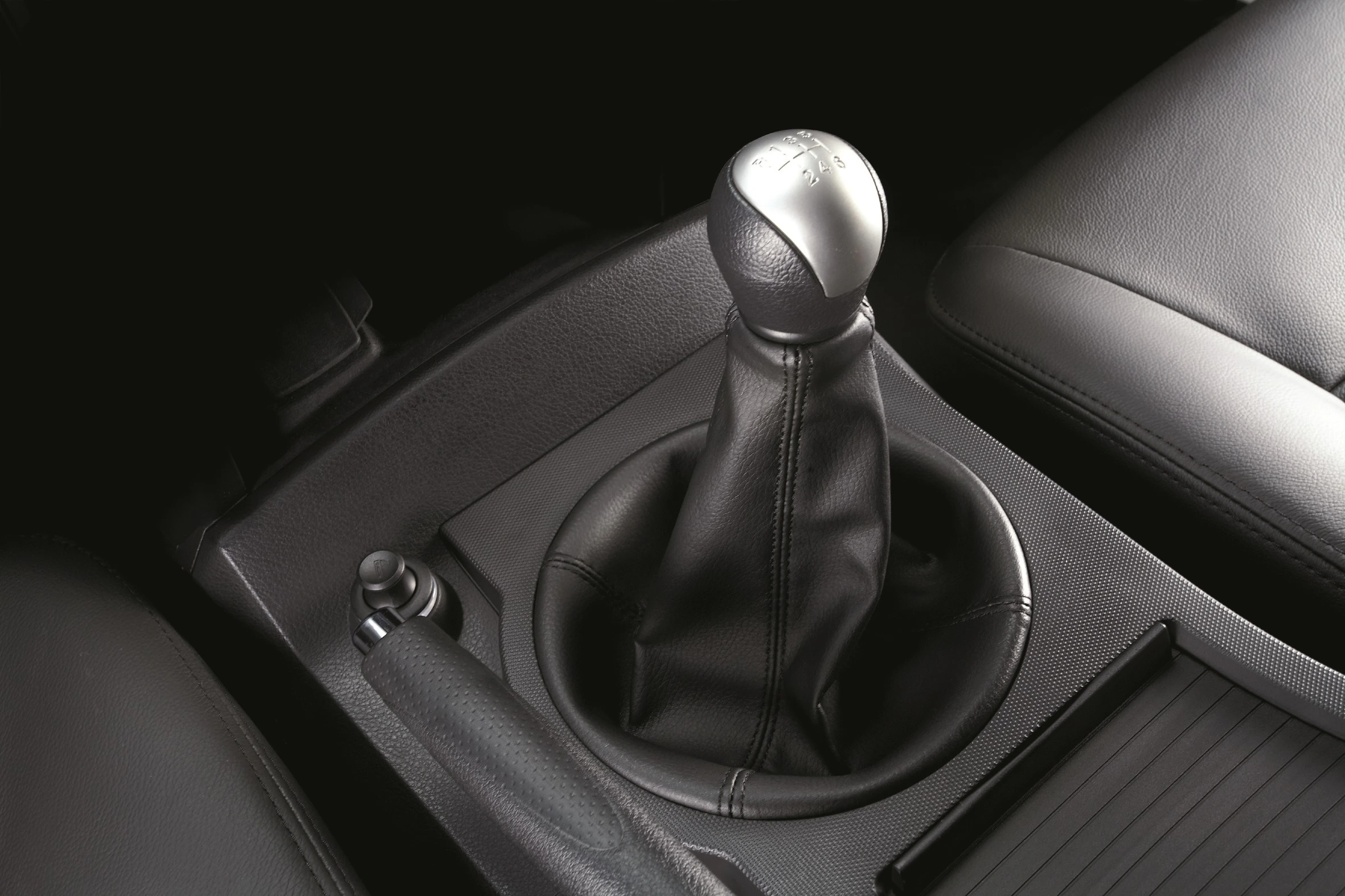 Handschaltung im Auto mit schwarzem Leder in einem modernen Interieur, neben einem kaputten Handbremshebel.