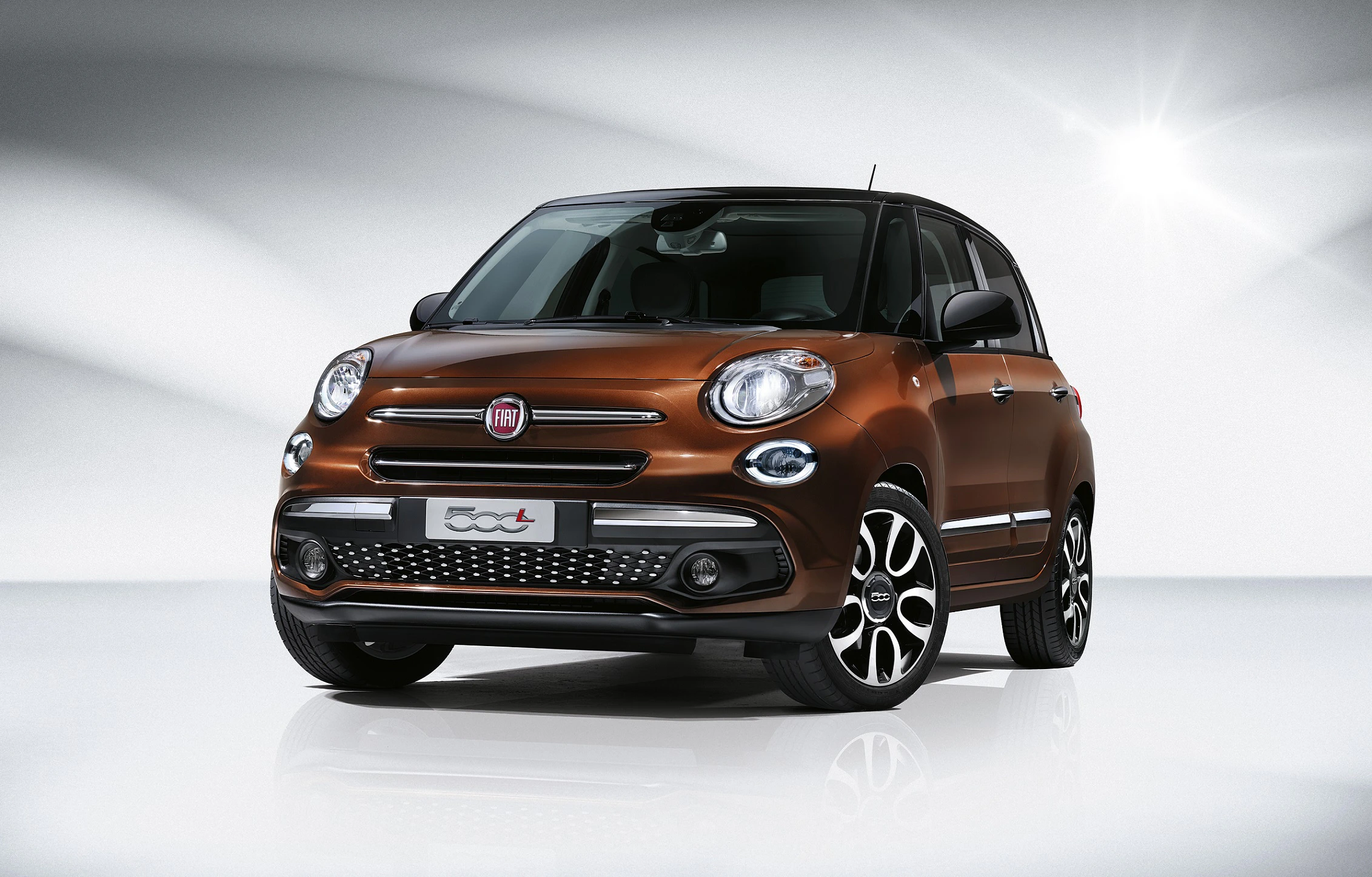 Brauner Fiat 500L auf hellem, modernem Hintergrund, leicht von vorne betrachtet, mit hervorgehobenen Chromdetails und markantem Design.