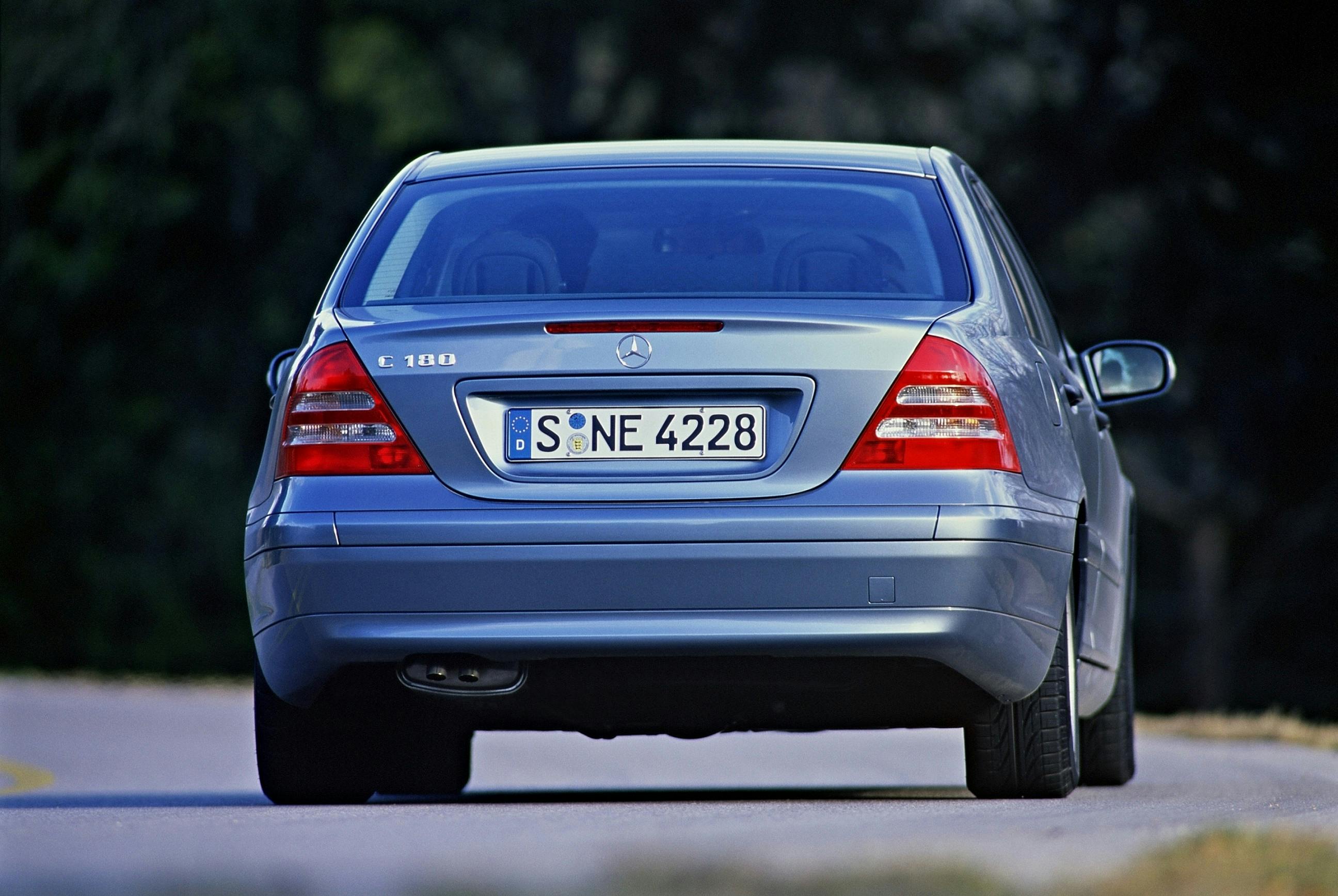 Silberner Mercedes-Benz C 180 von hinten auf einer Straße, mit deutschem Kennzeichen "S NE 4228", verschwommener Hintergrund.