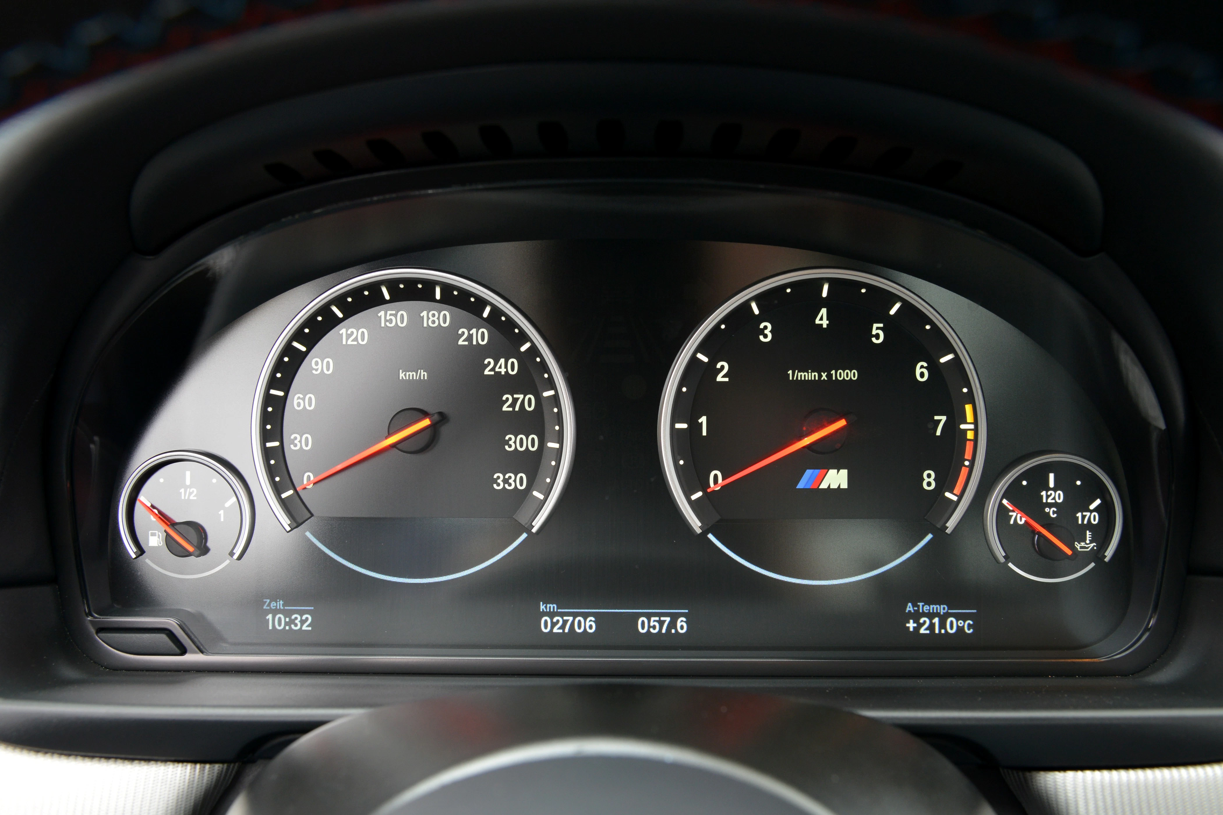 Nahaufnahme eines Auto-Tachometers mit Tachonadel bei 0 km/h und Drehzahlmesser bei 0 U/min. Kilometerstand: 2706 km, Außentemperatur: 21°C.