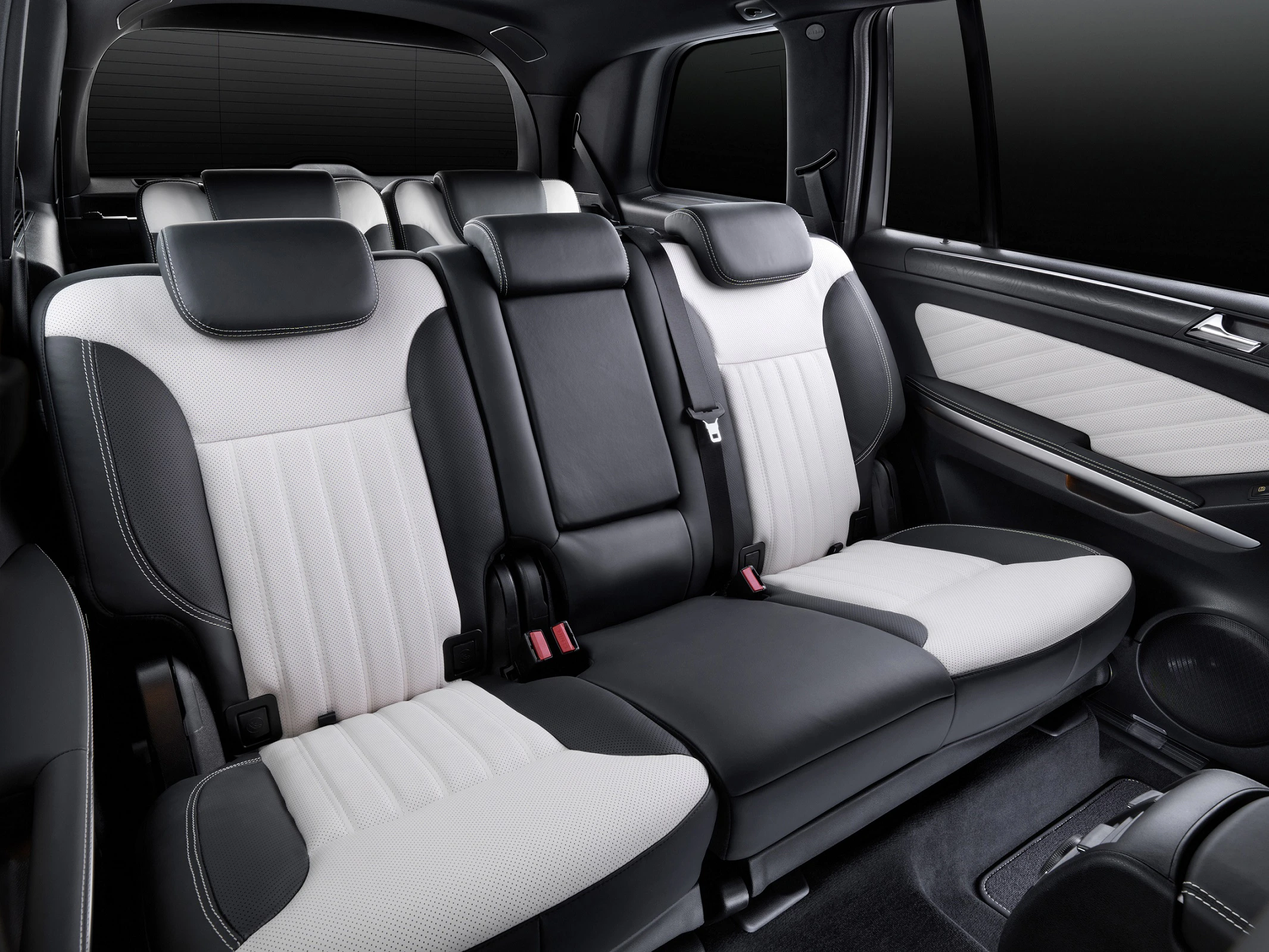 Schwarz-weiße Autositze in einem geräumigen Innenraum eines Fahrzeugs mit drei Sitzreihen. Hochwertige Polsterung und modernes Design.