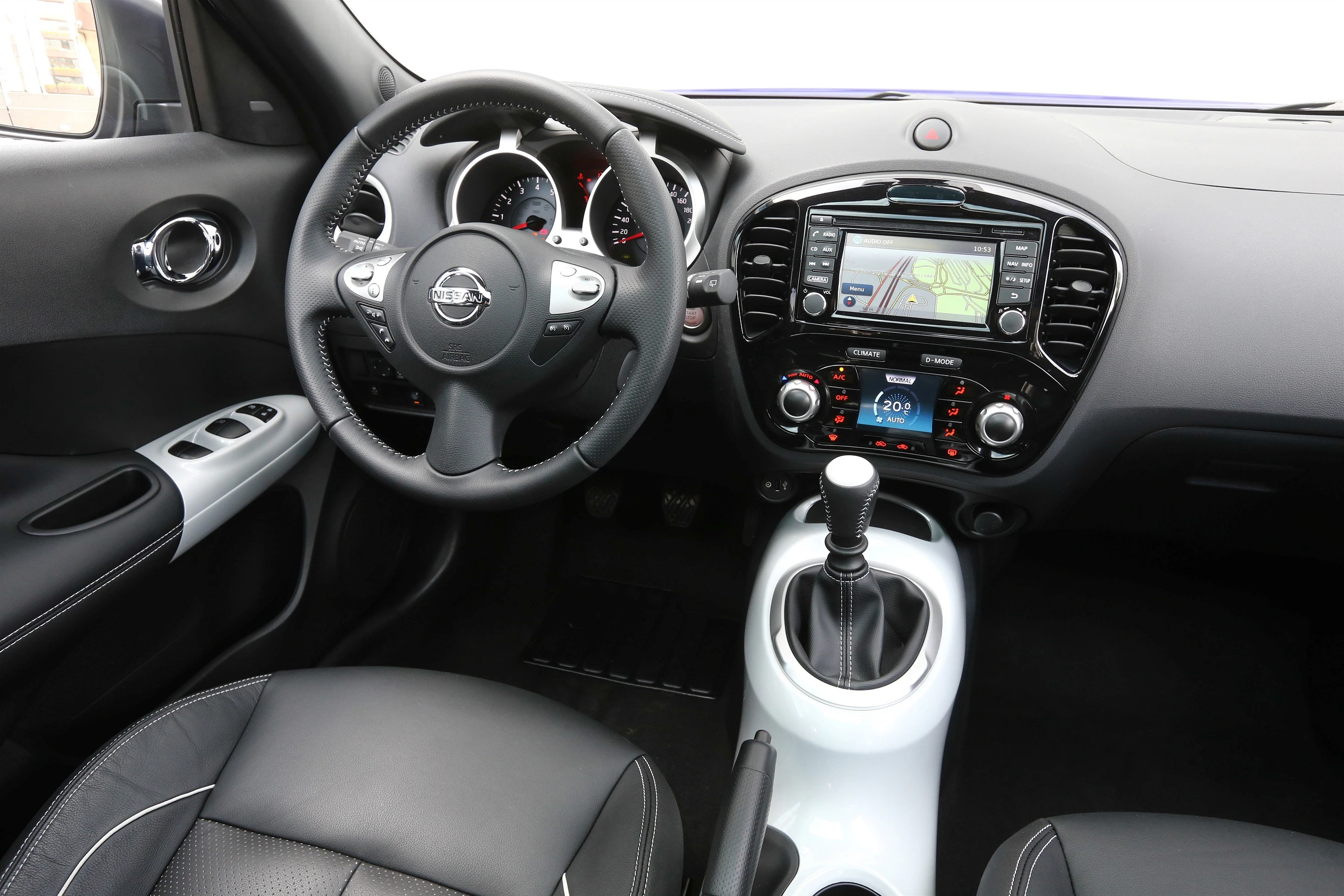 Innenraum eines Autos mit schwarzen Sitzen, Lenkrad, Gangschaltung, und zentralem Display, das eine Karte anzeigt. Moderne Ausstattung.