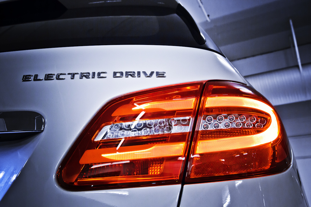 Nahaufnahme eines weißen Elektroautos mit leuchtendem Rücklicht und dem Schriftzug "ELECTRIC DRIVE" auf der Rückseite.