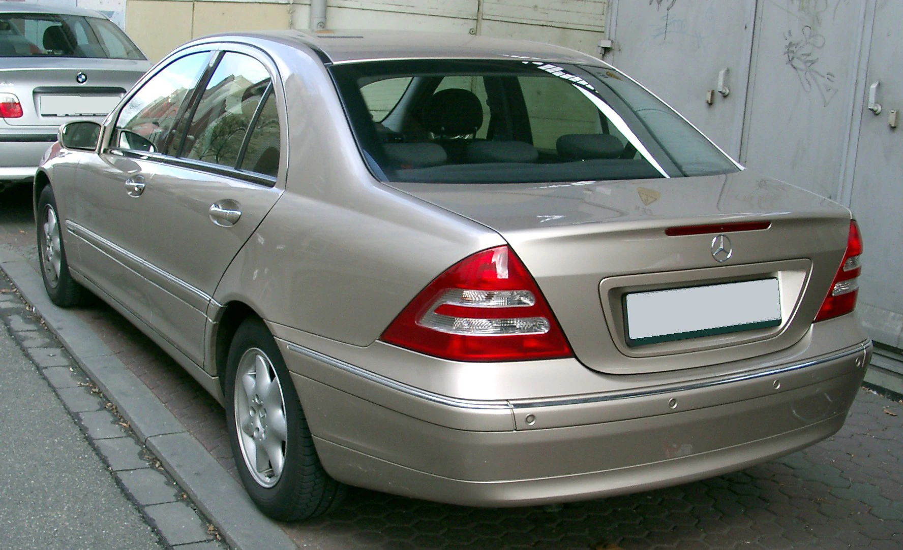 Silberner Mercedes-Benz C-Klasse der 2000er-Jahre, geparkt auf einer Straße, von hinten fotografiert.