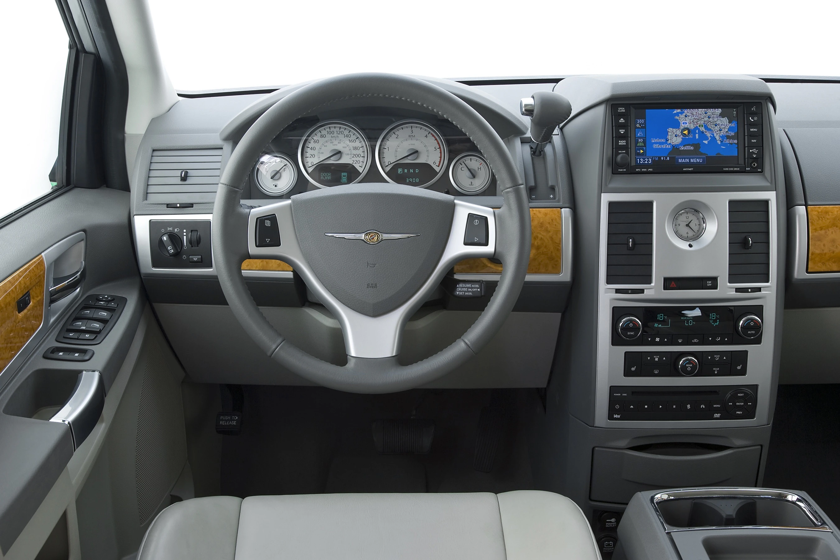 Armaturenbrett eines Autos mit Lenkrad, Holzverkleidung, Navigationssystem und klassischen Rundinstrumenten auf der Fahrerseite.