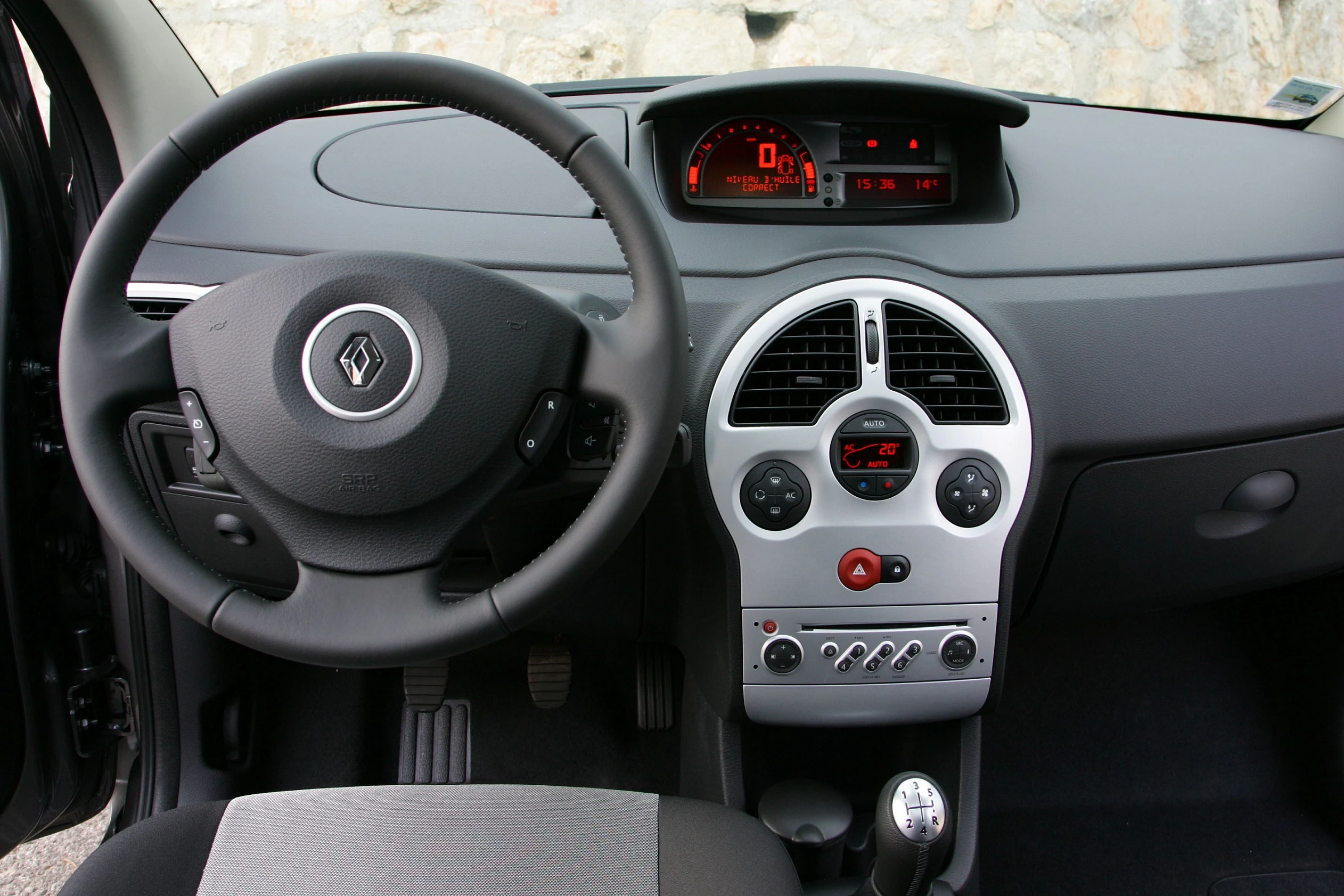 Lenkrad und Armaturenbrett eines Autos, schwarzes und graues Interieur, Digitalanzeigen und Bedienelemente in der Mittelkonsole.