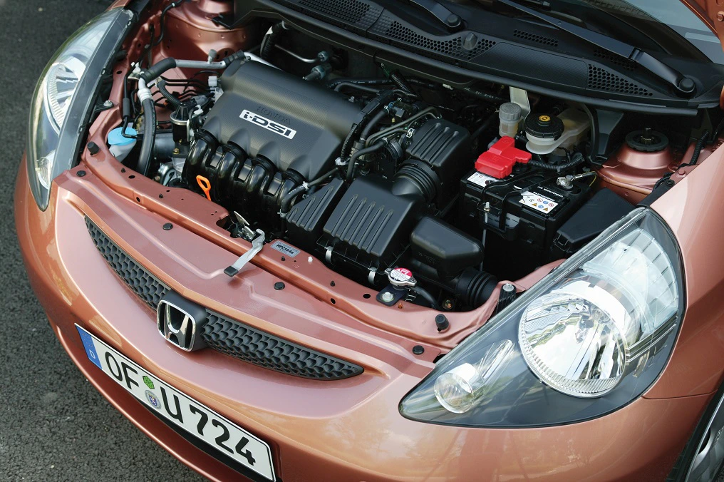 Motorraum eines Honda-Autos von oben, mit geöffnetem Kühlergrill. Sicht auf Motor, Batterie und andere Fahrzeugkomponenten.