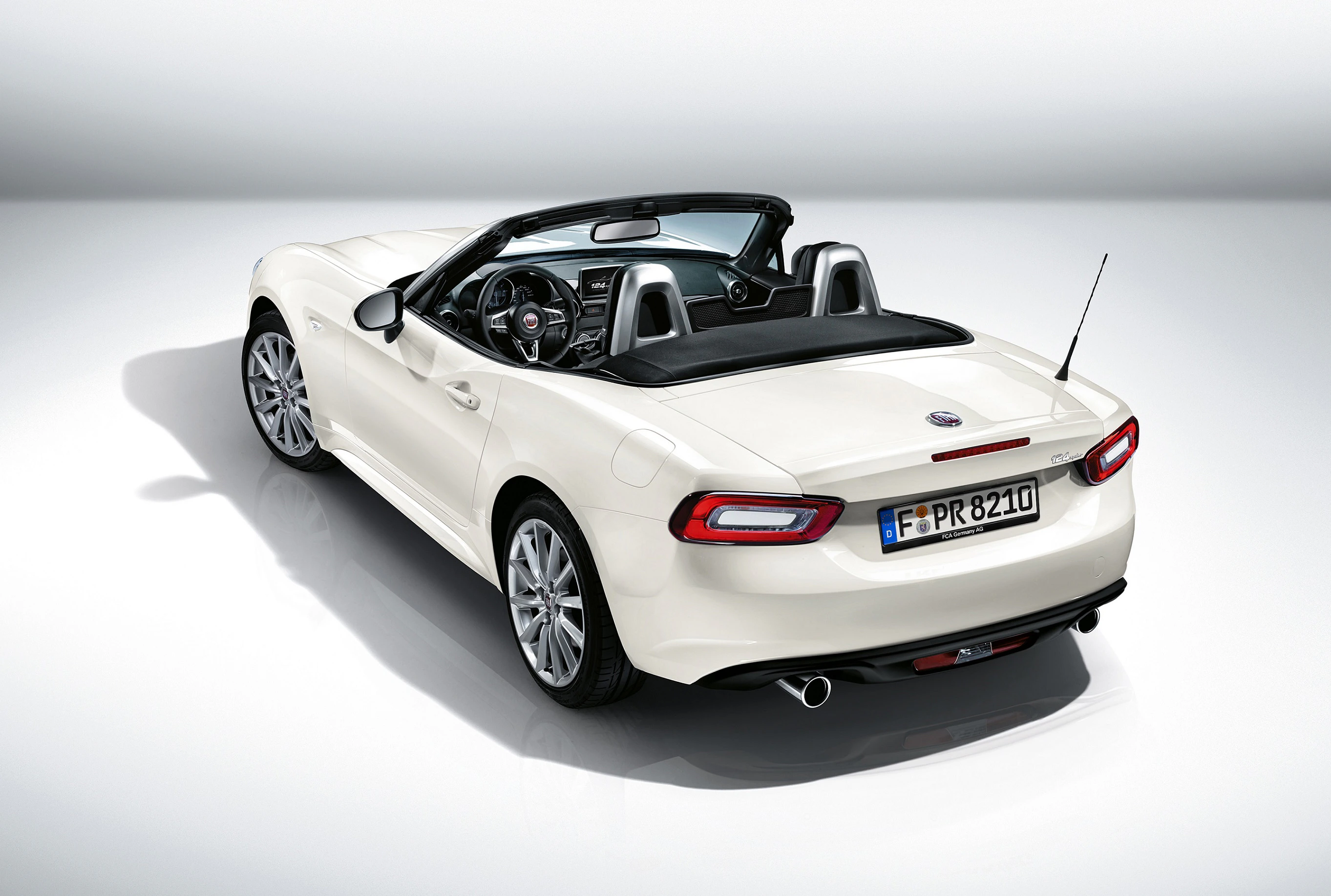 Weißer Cabrio-Sportwagen mit heruntergeklapptem Verdeck, von hinten fotografiert. Sichtbar sind die Rücklichter und das Innere des Fahrzeugs.