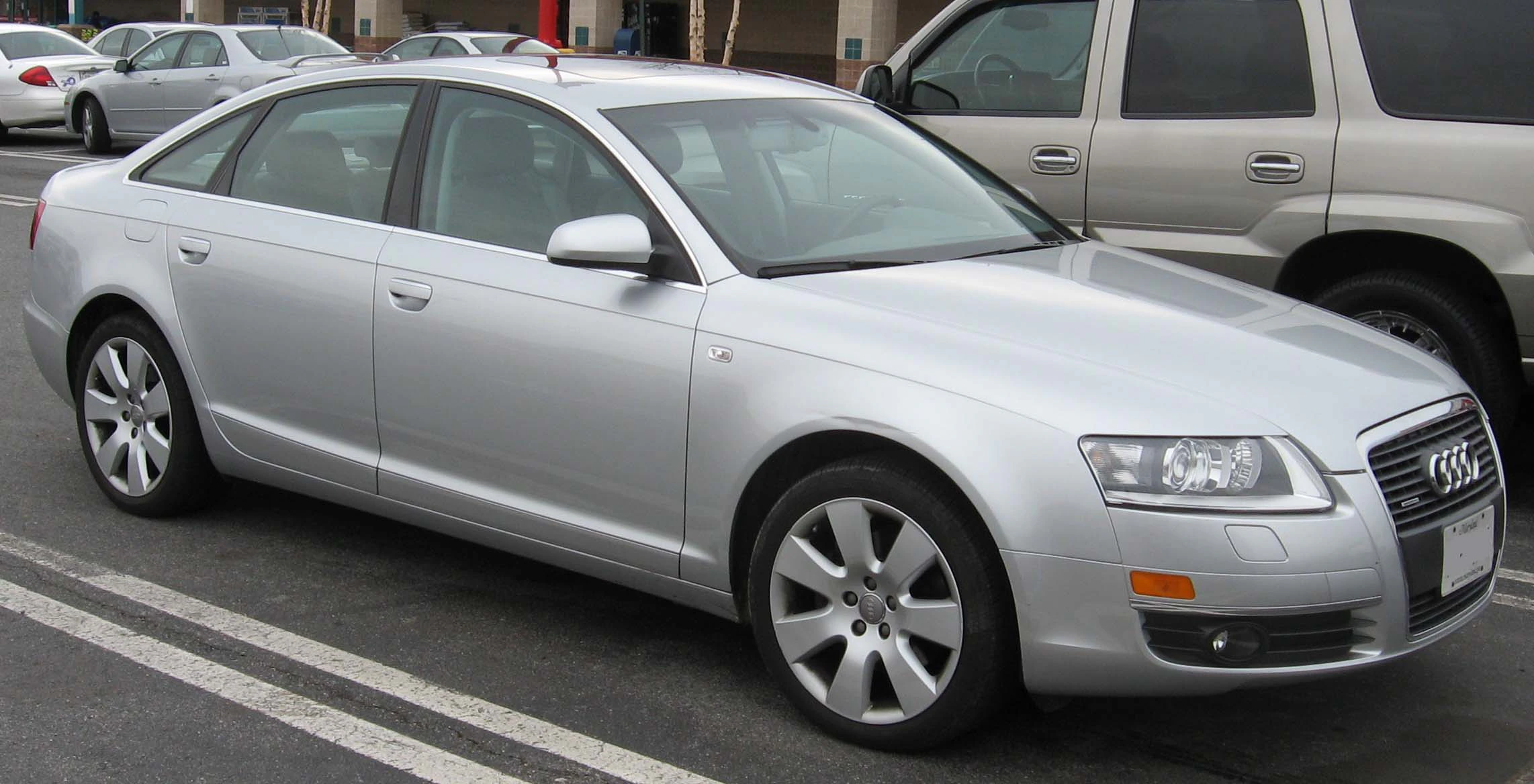 Silberner Audi A6, Limousine, geparkt auf einem Parkplatz neben anderen Fahrzeugen.