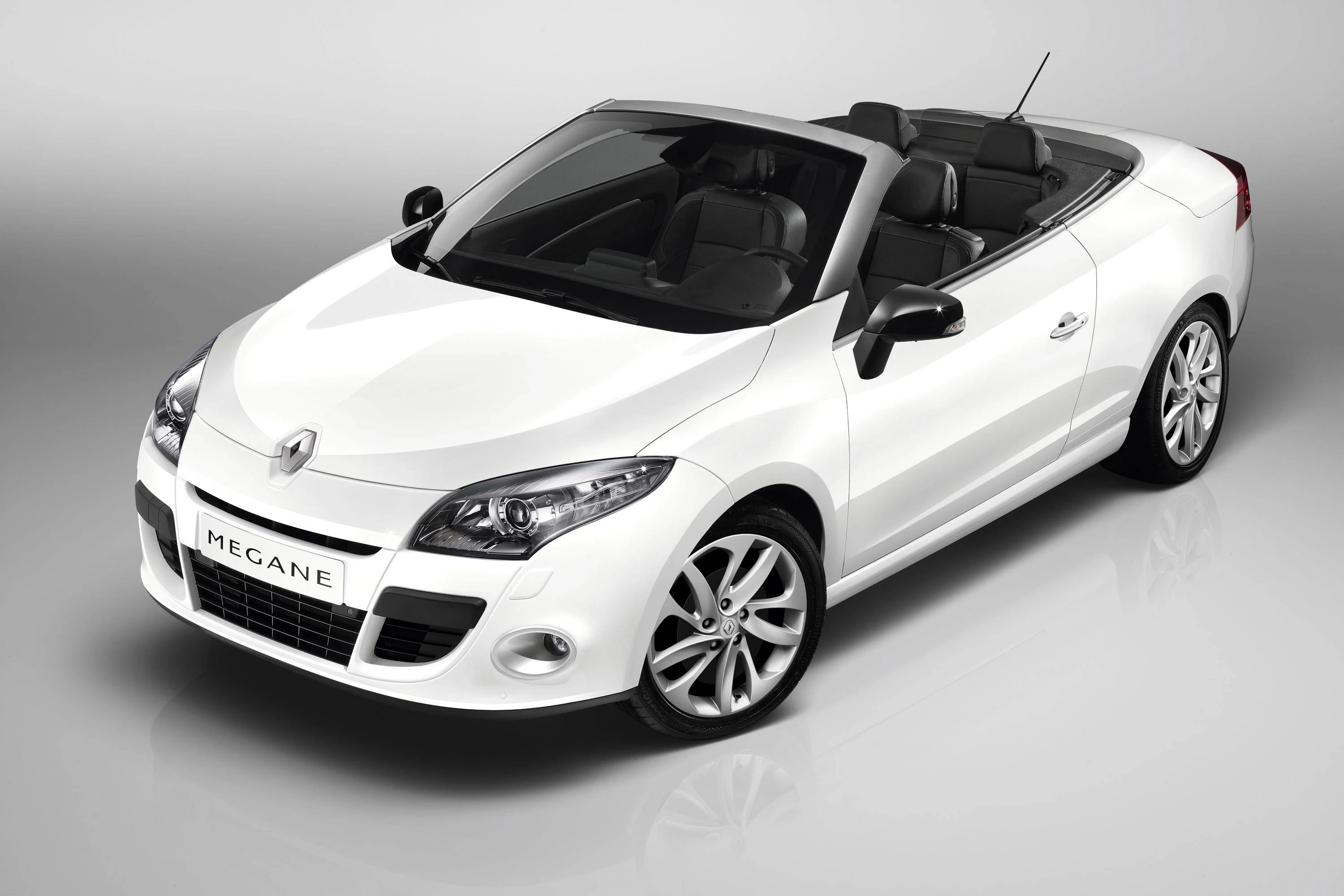 Weißes Cabriolet-Auto mit schwarzem Interieur, geparkt in einem Studio mit der Aufschrift "Megane" auf dem Nummernschild.