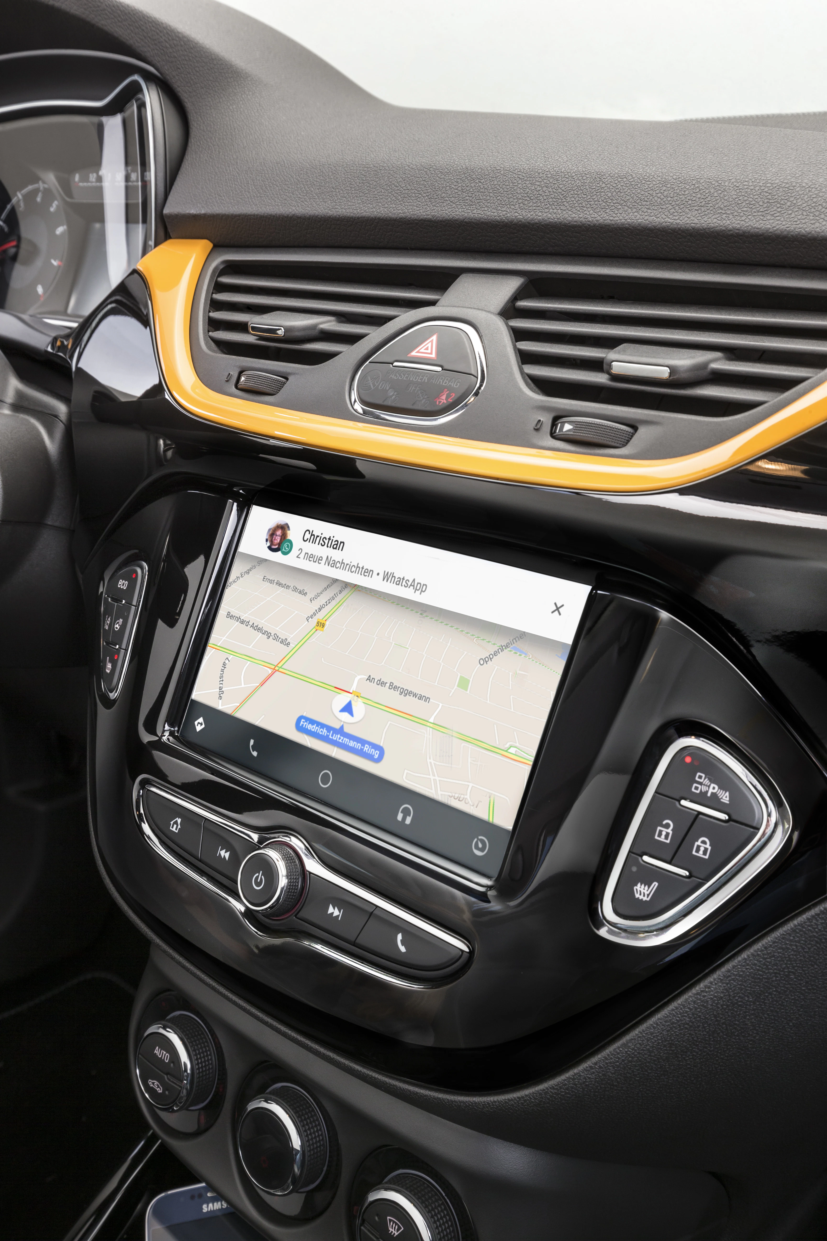 Navigationssystem in einem Auto mit Touchscreen, zeigt eine geöffnete WhatsApp-Nachricht und eine Kartenansicht auf dem Display.