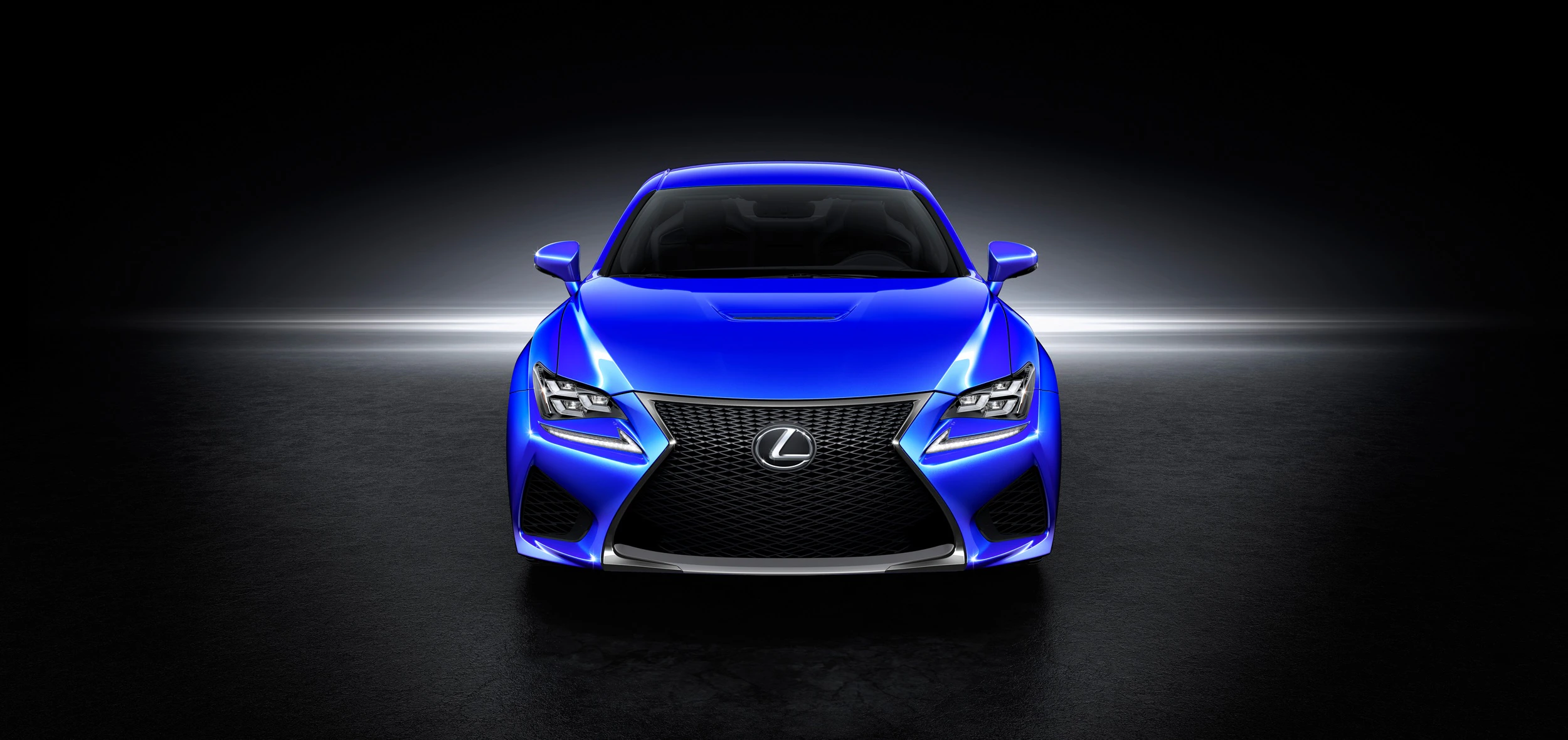 Blauer Sportwagen von Lexus in dunkler Umgebung, von vorn fotografiert. Fahrzeugdetails und Scheinwerfer sind beleuchtet.
