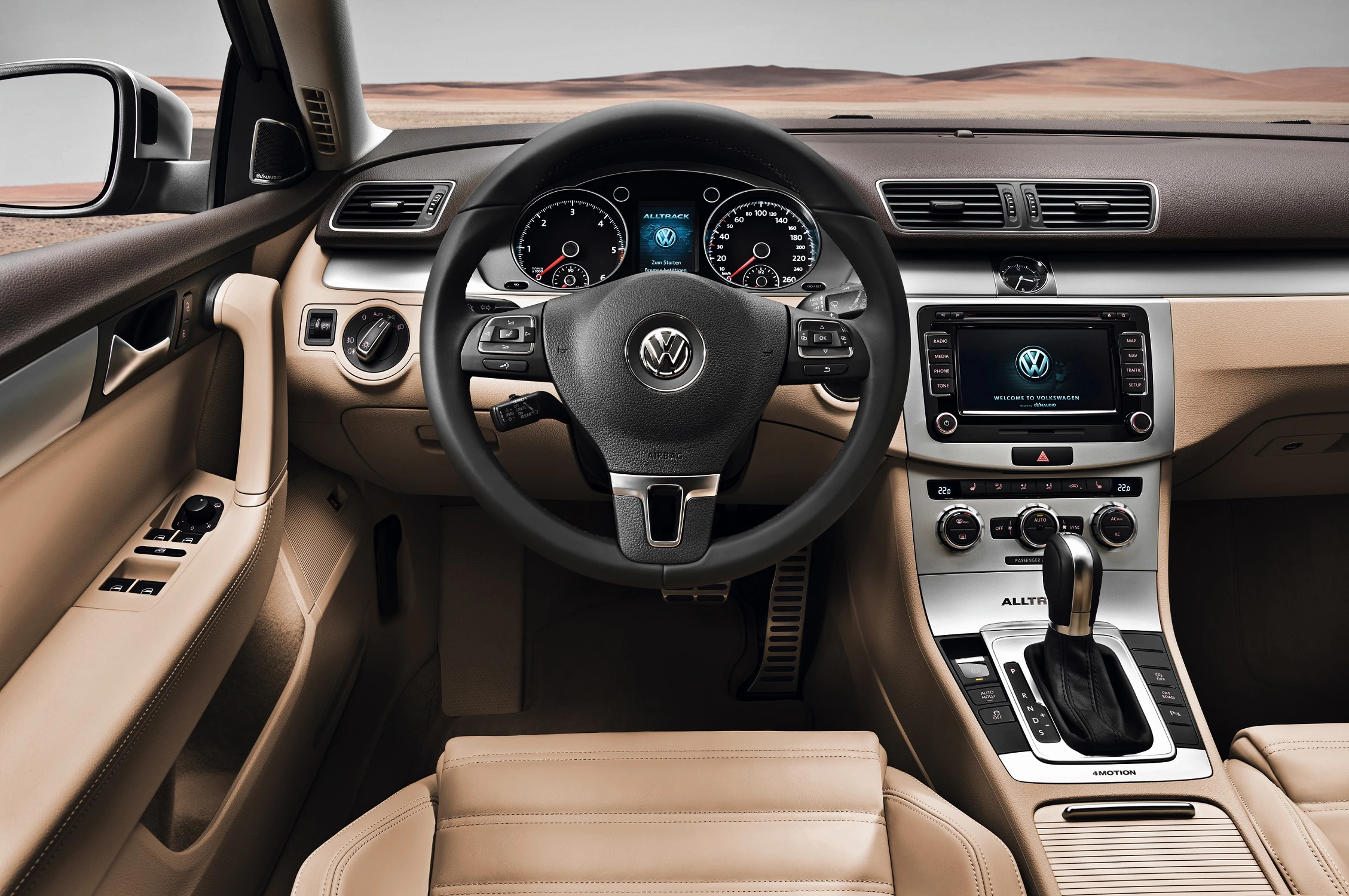 Innenraum eines Volkswagen-Autos mit Lederpolstern, Multifunktionslenkrad und Touchscreen-Display, im Hintergrund Wüstenlandschaft.