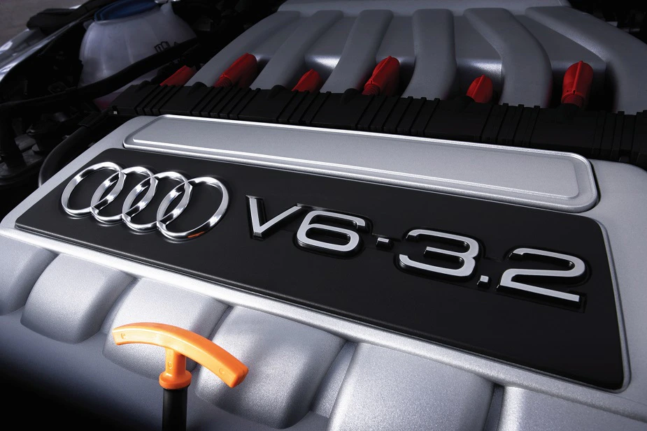 Nahaufnahme eines Audi V6-3.2-Motors, mit silbernem Gehäuse und orangefarbenem Ölmessstab im Vordergrund.