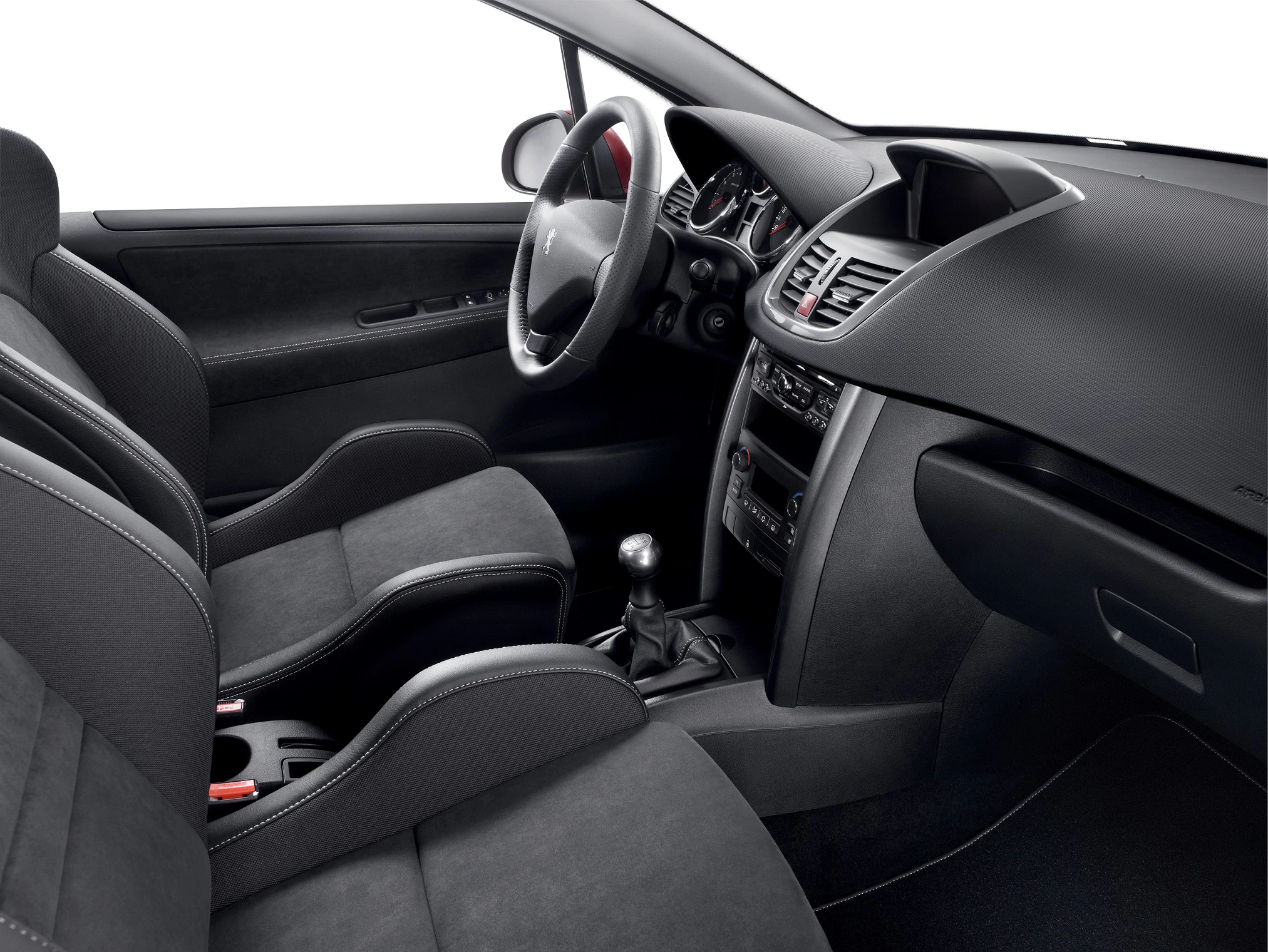 Innenraum eines modernen Autos mit schwarzen Sitzen, Lenkrad links, Schalthebel, Armaturenbrett und Mittelkonsole mit Bedienelementen.