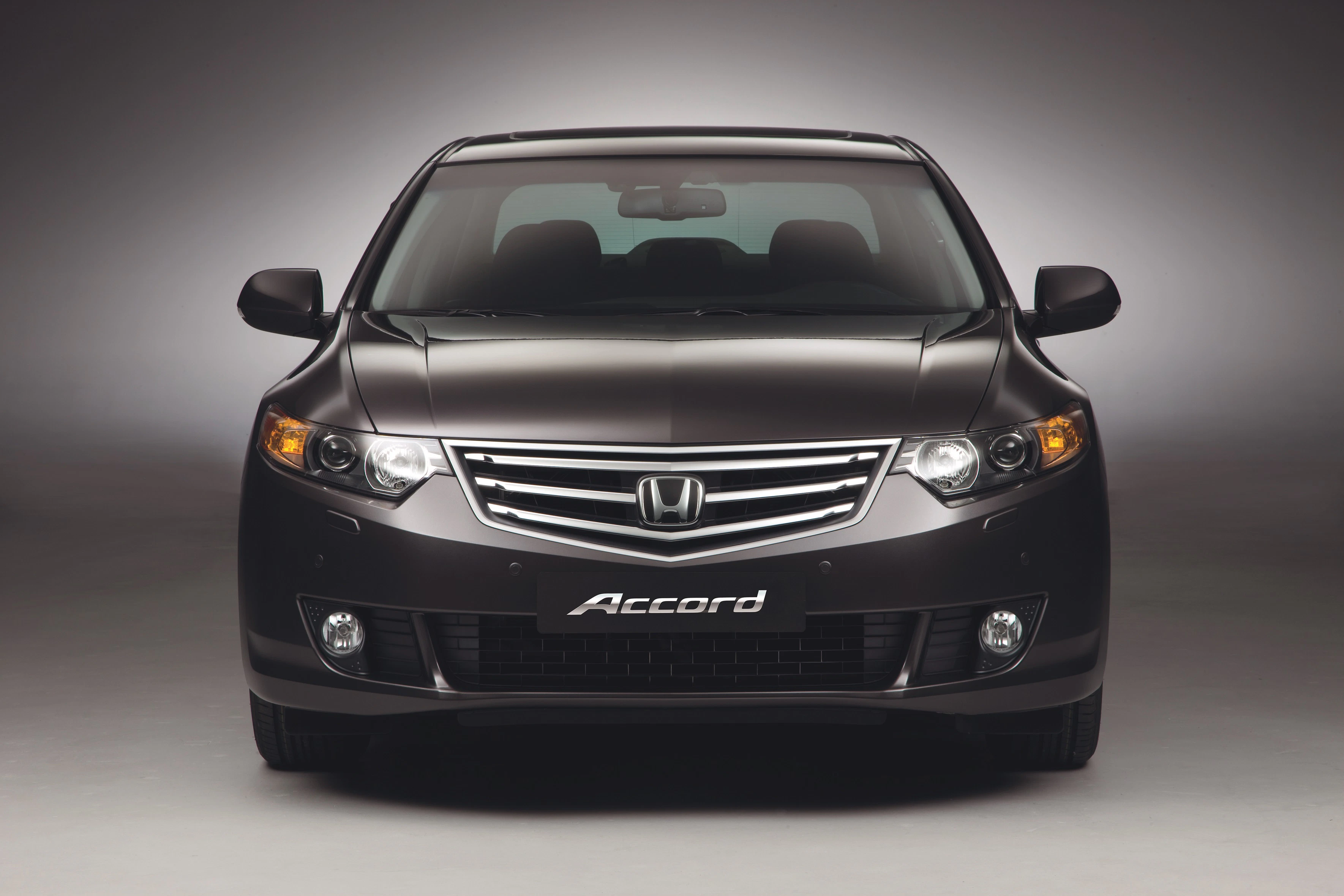 Vorderansicht eines dunkelgrauen Honda Accord mit markantem Kühlergrill und Scheinwerfern, auf neutralem Hintergrund präsentiert.