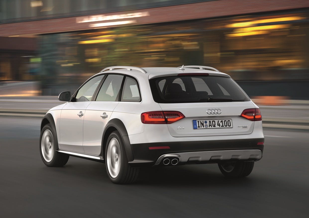 Silberner Audi A4 Allroad fährt schnell durch städtische Umgebung, Bewegungsunschärfe hinter dem Auto, fokussiert auf Rückseite und Auspuff.