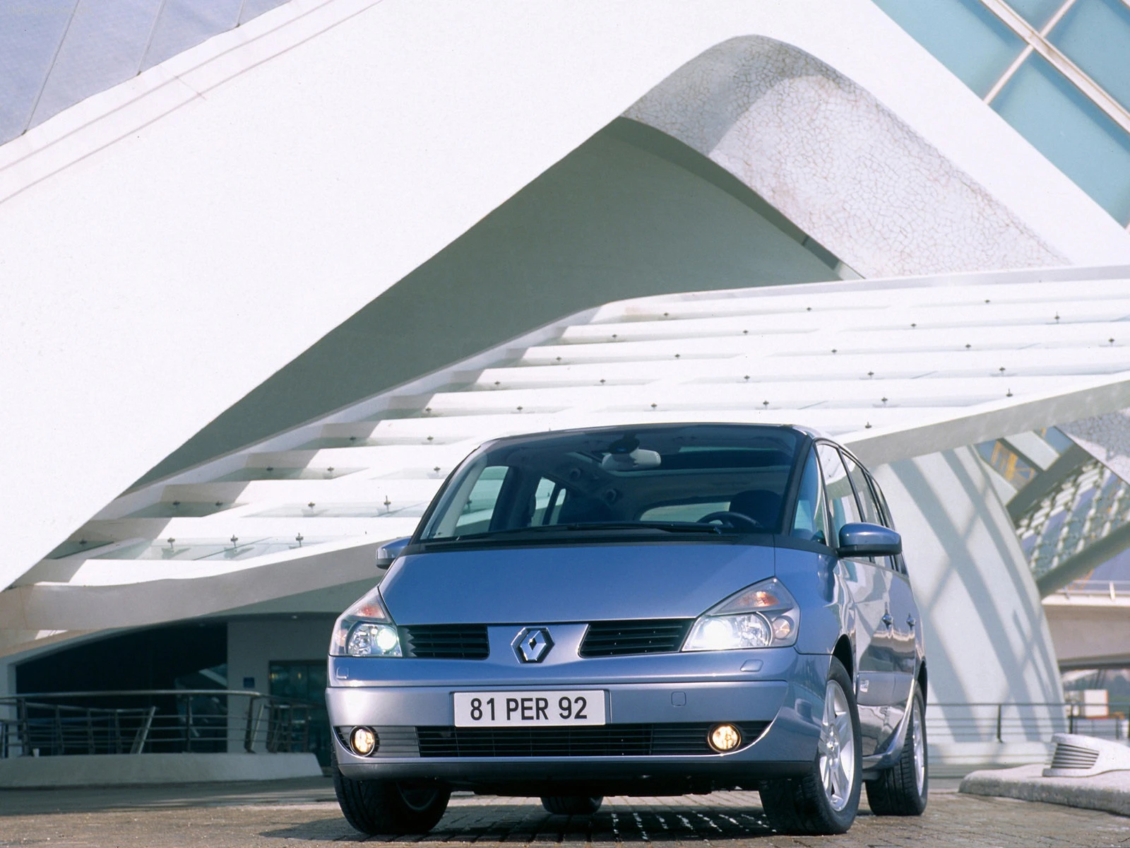 Silberner Renault Espace steht vor moderner, weißer Architektur. Vorderansicht des Autos mit Nummernschild "81 PER 92".